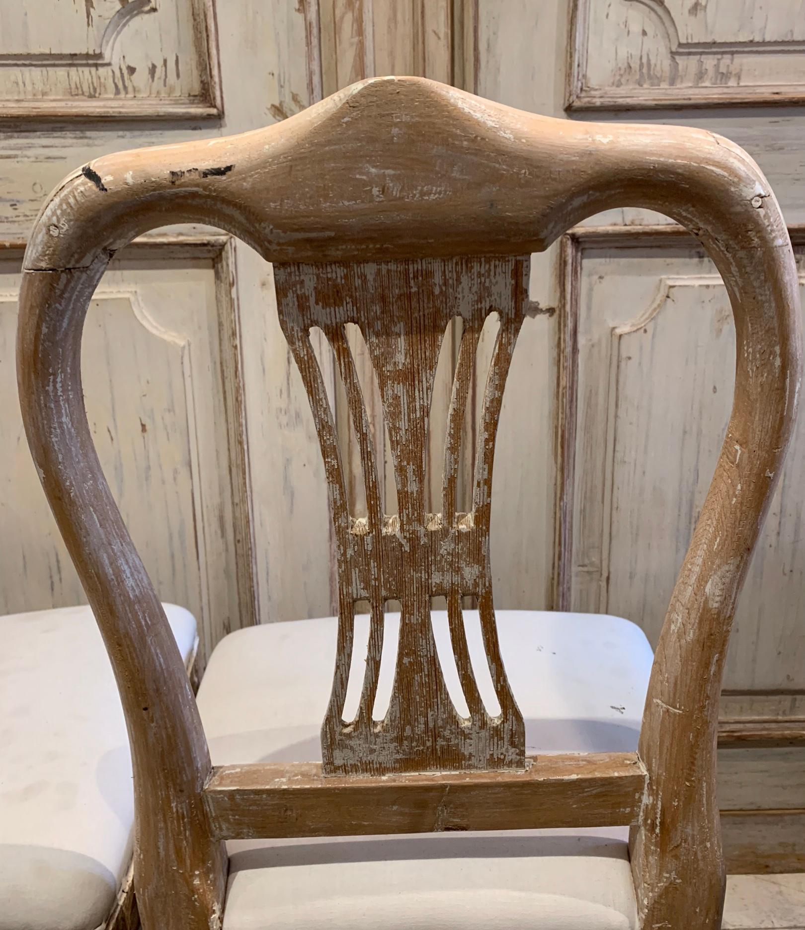 Set of four charming Swedish folk dining chairs which are made of pine. There are still some traces of historic paint on the chairs but they have been scraped back to the bare wood which gives them a more rustic feel.

Recently reupholstered in a