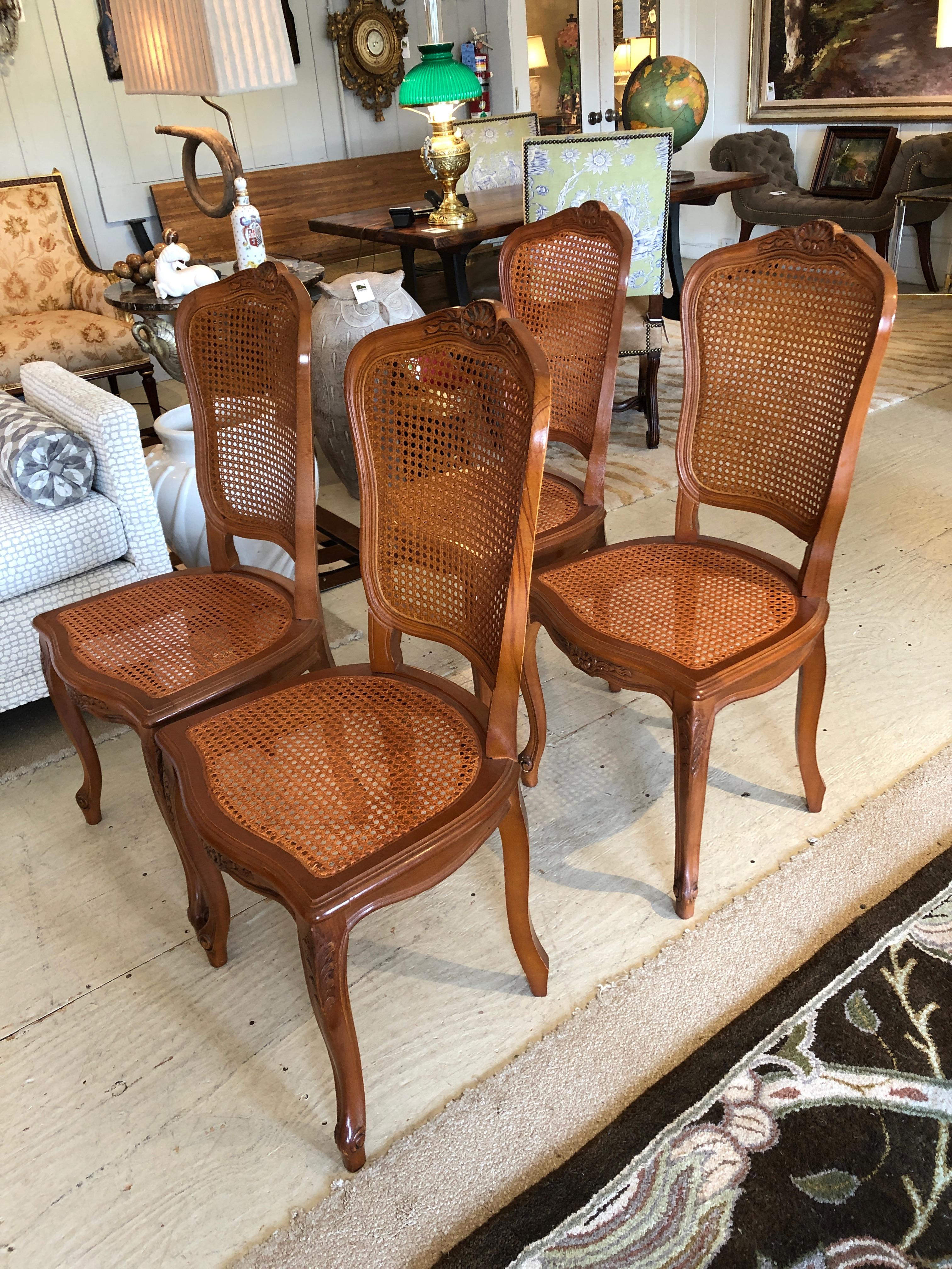 A Classic French style set of 4 side dining chairs having carved wood frames and caned backs and seats. 
Measures: Seat height 17.5.