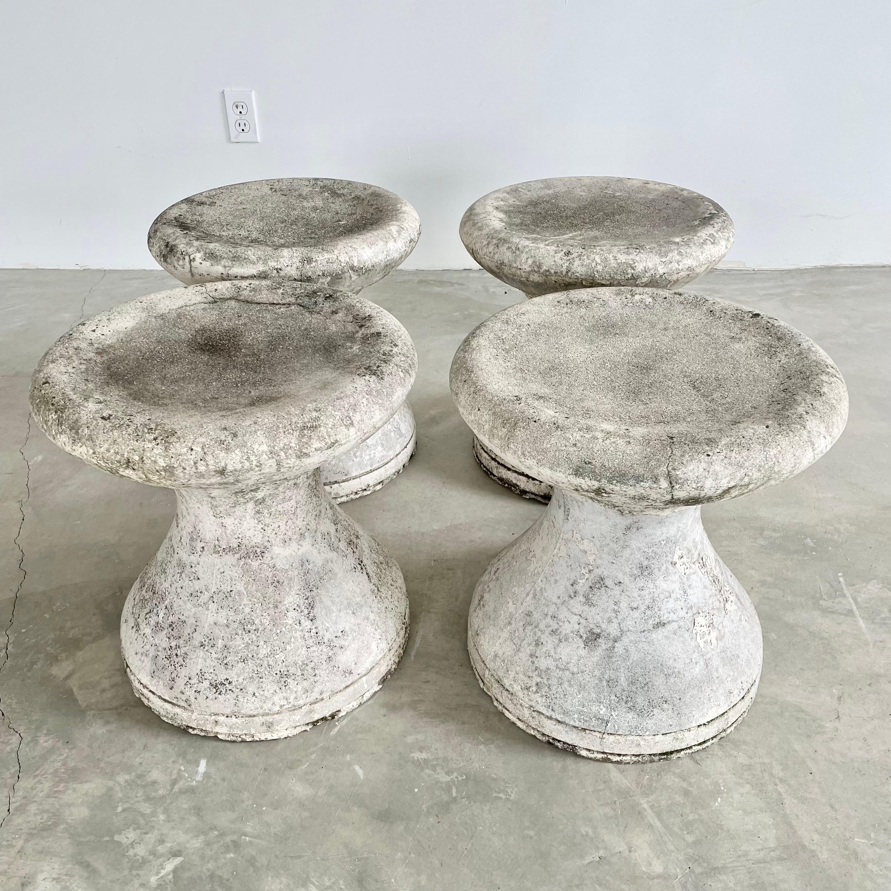 Stunning French concrete hourglass stools, circa 1970s. Minimalist design with delicate rims on the top and bottom and a concave body that expands at the seat and the base. A unique set that can easily fit into any space. Years of patina and