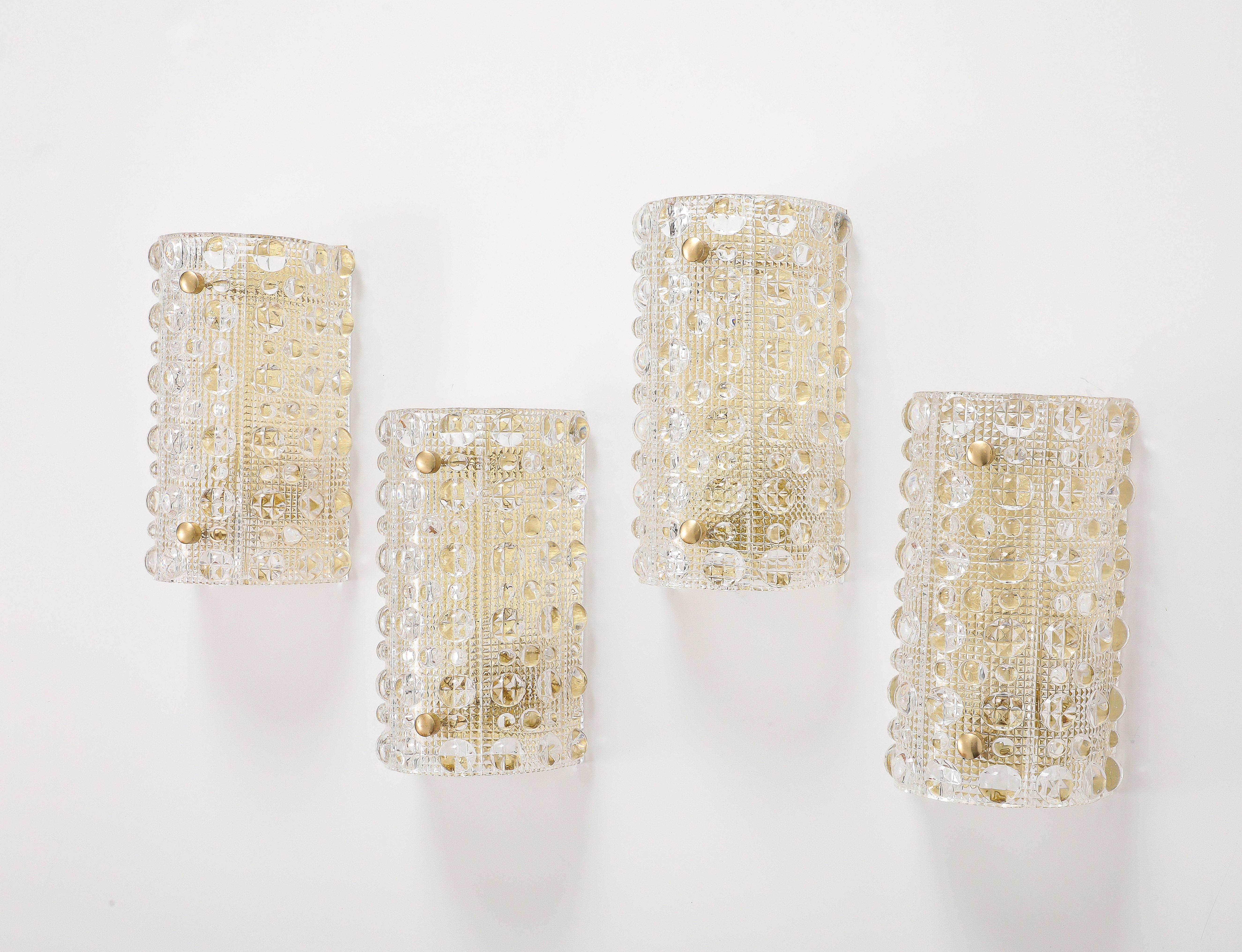 Glamorous set of 4 large 1960's  Crystal sconces designed by carl Fagerlund for Orrefors.
The beautiful  crystal bubble patterned  glass is formed in a half circle which sits on a minimalist brass base held on by two simple brass knobs.
The sconces