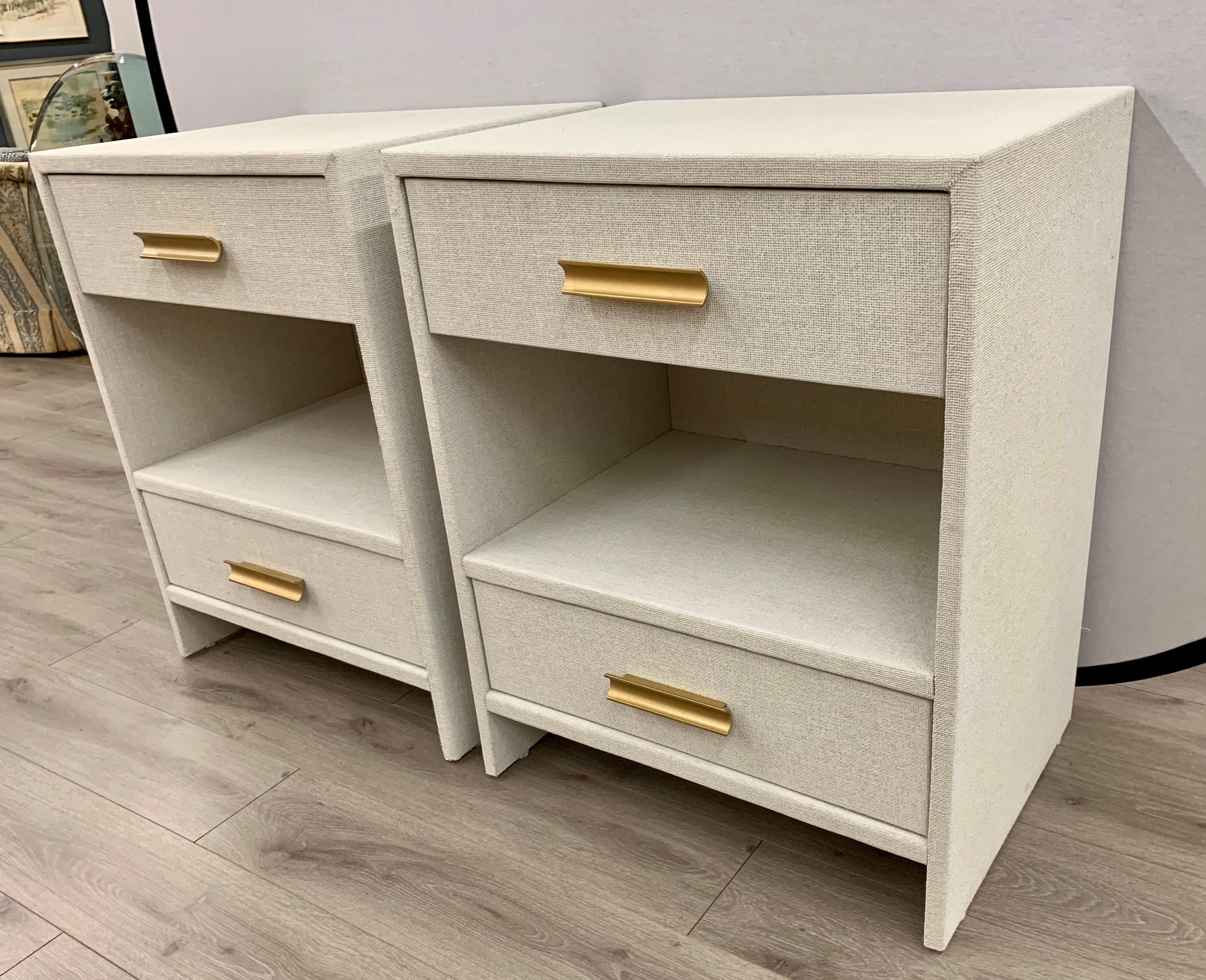 Sleek, simple lines give these nightstands a Mid-Century Modern feel and are wrapped by hand in fine linen then given a multi-layered paint glaze in a neutral oyster color. They have two drawers with a center shelf. Brass handles give it a