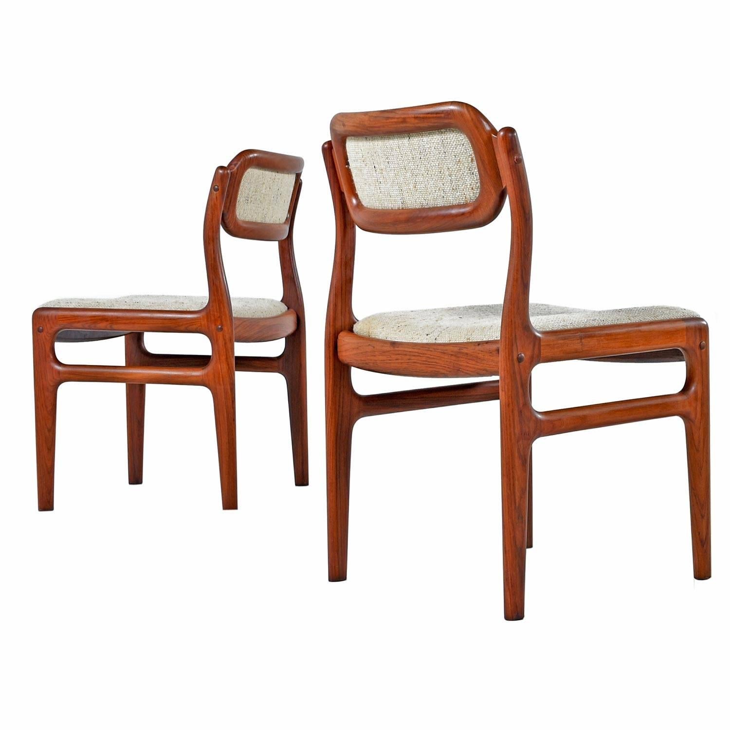 A set of four rosewood dining chairs, in the style of Niels O. Møller by Johannes Andersen for Uldum Møbelfabrik. The several decades old solid rosewood has a rich red patina that bounces beautifully against the original wool fabric.