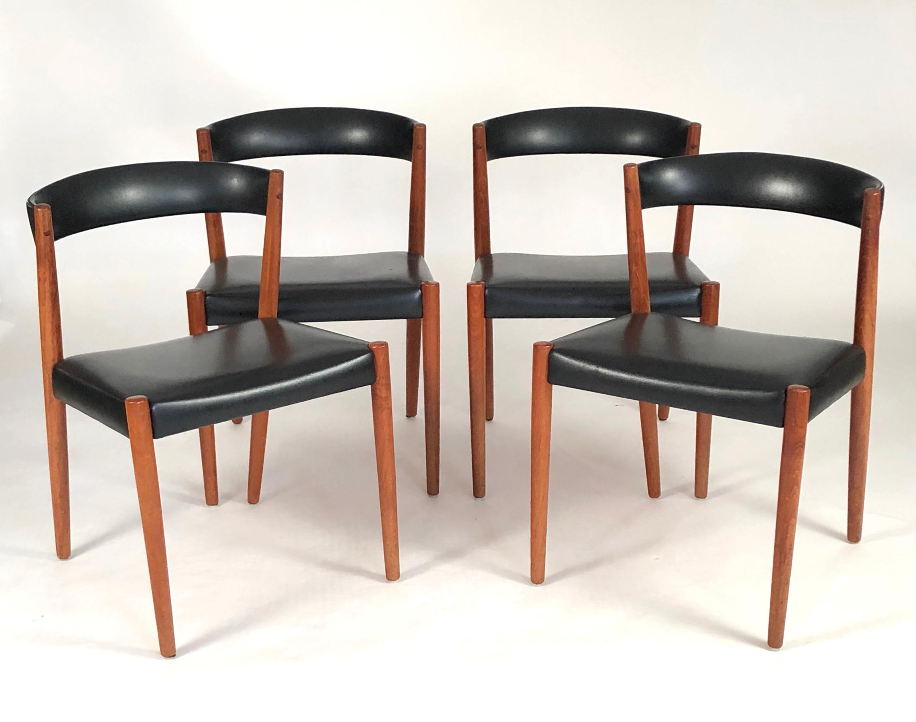 A set of 4 Danish Mid-Century Modern chairs in teak, with curved black leather upholstered backs and seats. Great sculptural form and comfortable. These chairs would also work well at a games table, breakfast table, as side chairs, at a desk or