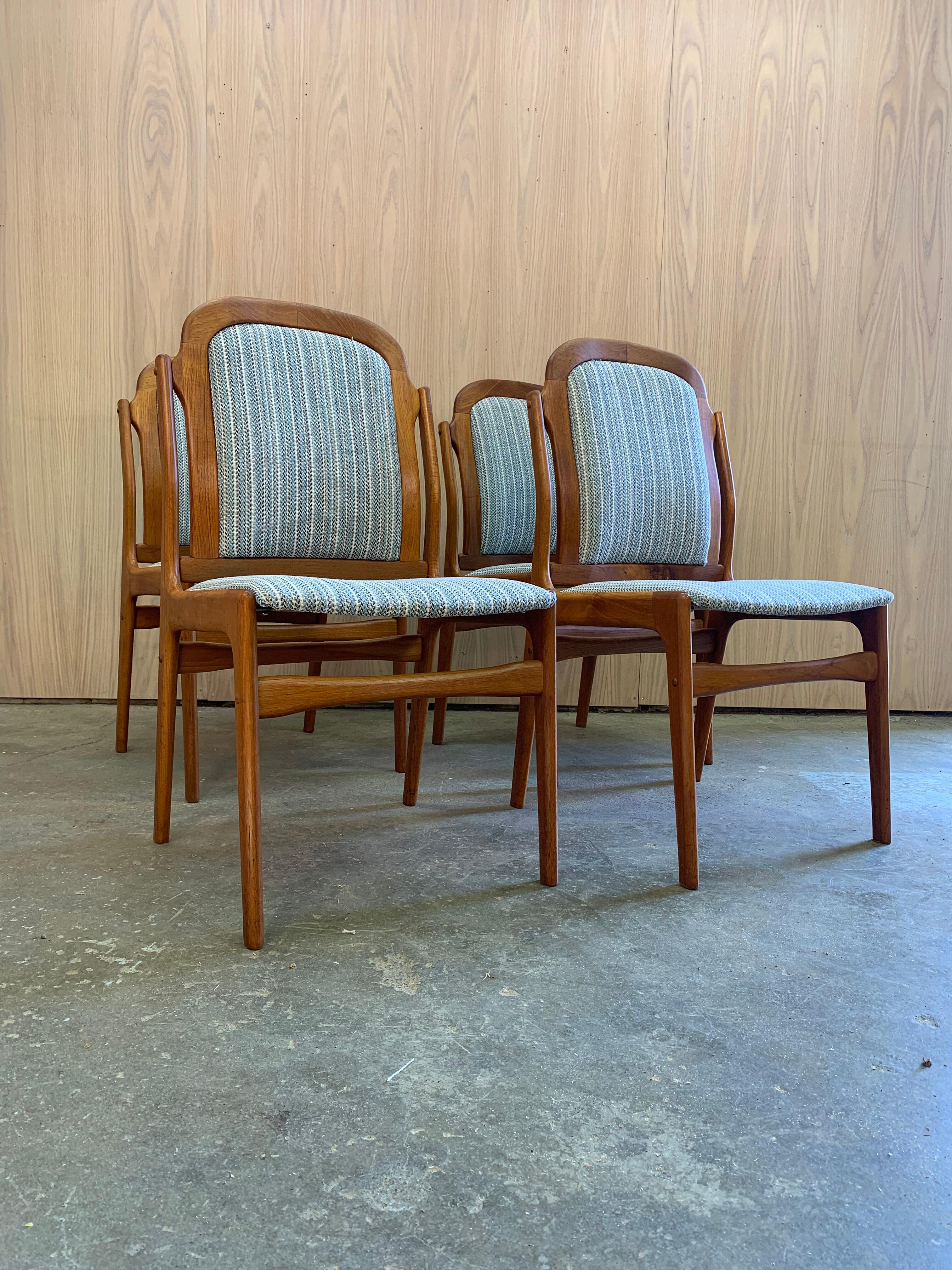 Un set di quattro sedie da pranzo danesi degli anni '70, splendidamente scolpite, realizzate in teak massiccio con curve morbide e raffinata falegnameria. Completamente restaurate dal nostro team e appena rivestite in un lussuoso tessuto in misto