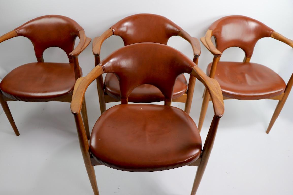 Stylish set of four Mid-Century Modern armchairs, attributed to Gunlocke. Sculptural solid walnut frames with brown leatherette seats and backs (some upholstery shows minor wear, as shown). Chic architectural design, high quality construction and