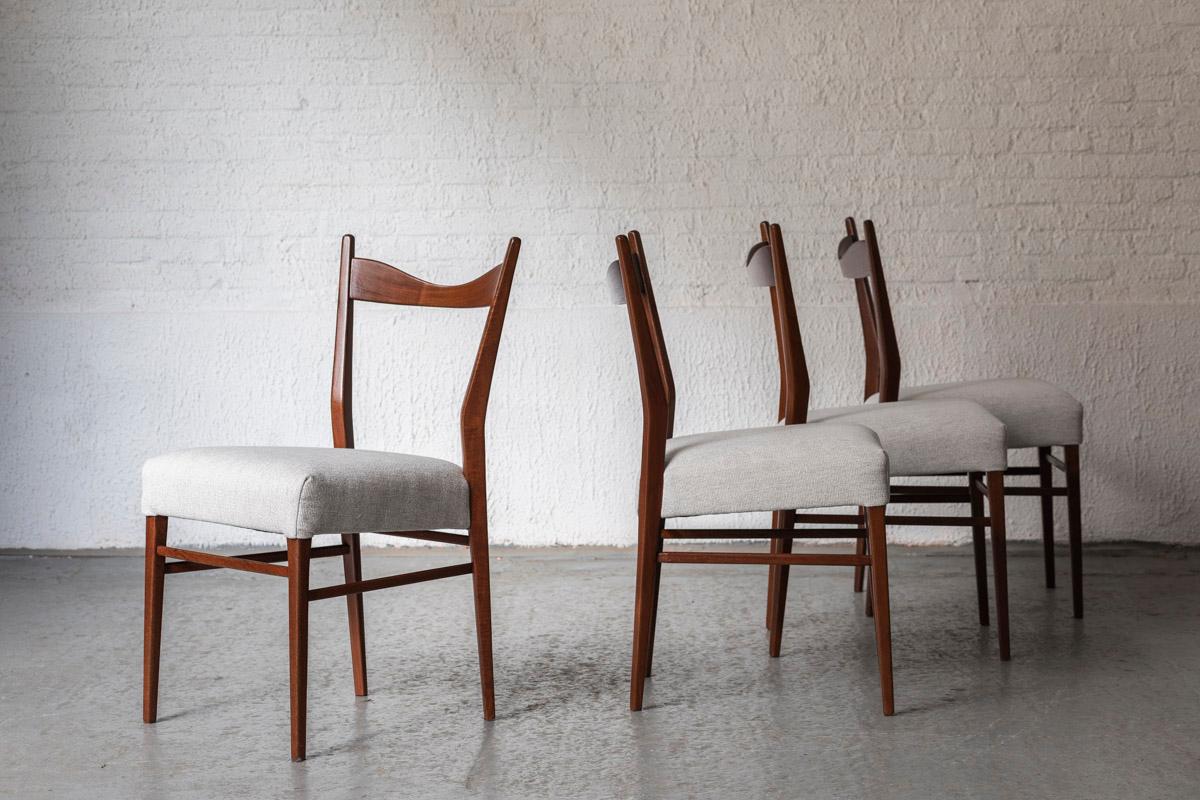 Set of 4 dining chairs designed and produced in Belgium in the 1950s. Teak frame and a white- light grey upholstery. One corner of one the backrests has been restored neatly. The chairs were completely renovated with new singles, new