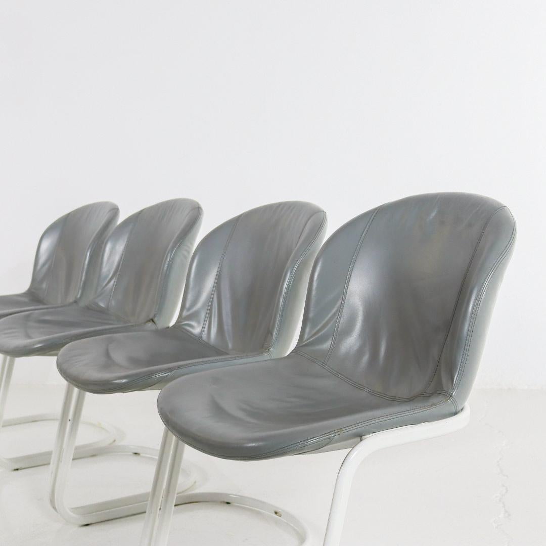 Set of 4 dining chairs by Gastone Rinaldi for Thema Italy. The chairs from the 1970s feature a white metal frame and are upholstered in gray/blue leatherette. The set is in good vintage condition, with light signs of use consistent with age.