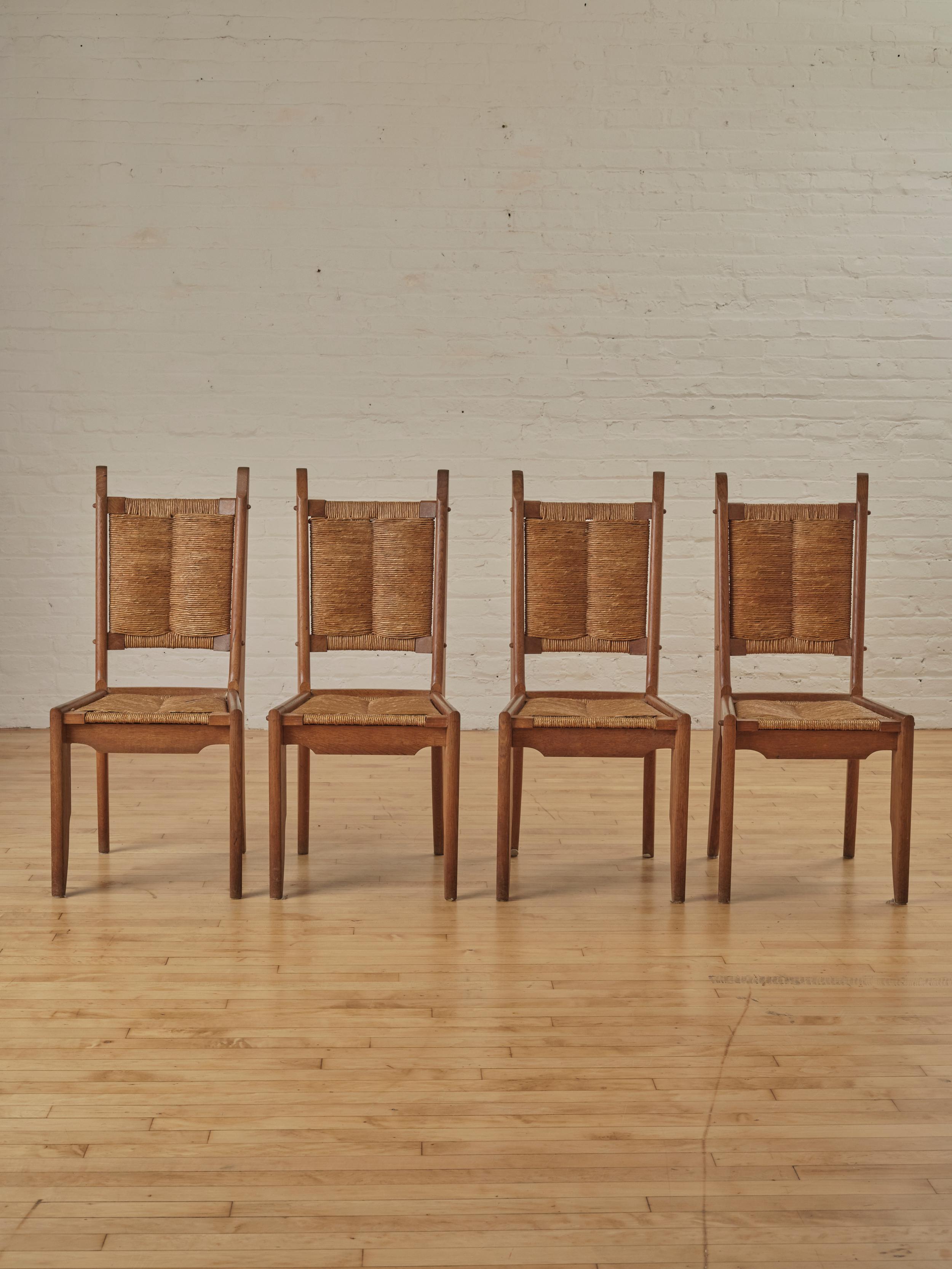 A set of four dining chairs in oakwood and straw, designed by Guillerme and Chambron for Notre Maison in the 1950s

