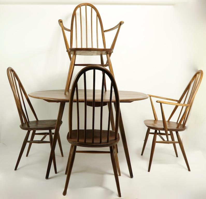 Set of 4 midcentury dining chairs designed by Lucien Ercolani for Ercol, made in England. These chairs are a modernist reinterpretation of the Classic Windsor chair, the set consist of 2-arm, and 2 armless chairs. All four are structurally sound,