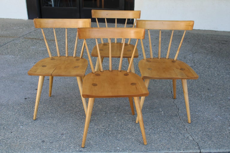 Set of four dining chairs designed by Paul McCobb for the Winchendon Furniture (Planner Group) Co. Solid maple with a spindle supported backrest and signature inlay screw on each seat. Each chair measures 19