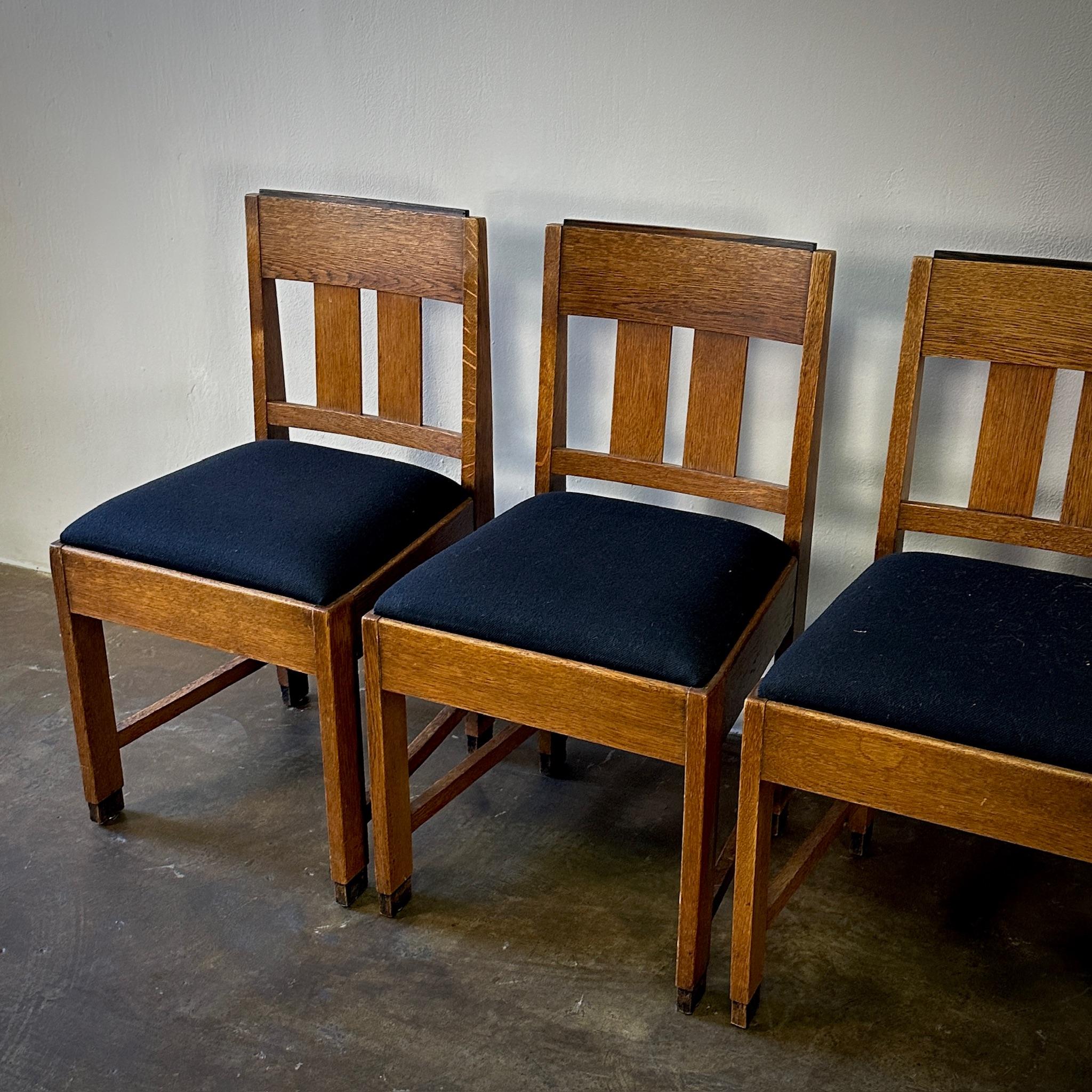Questo quartetto di sedie da pranzo della Scuola di Amsterdam, realizzate in legno di quercia e con sedute imbottite di nero, presenta un'elegante silhouette modernista. Il loro design è unico e allo stesso tempo sobrio, per cui sono un'aggiunta