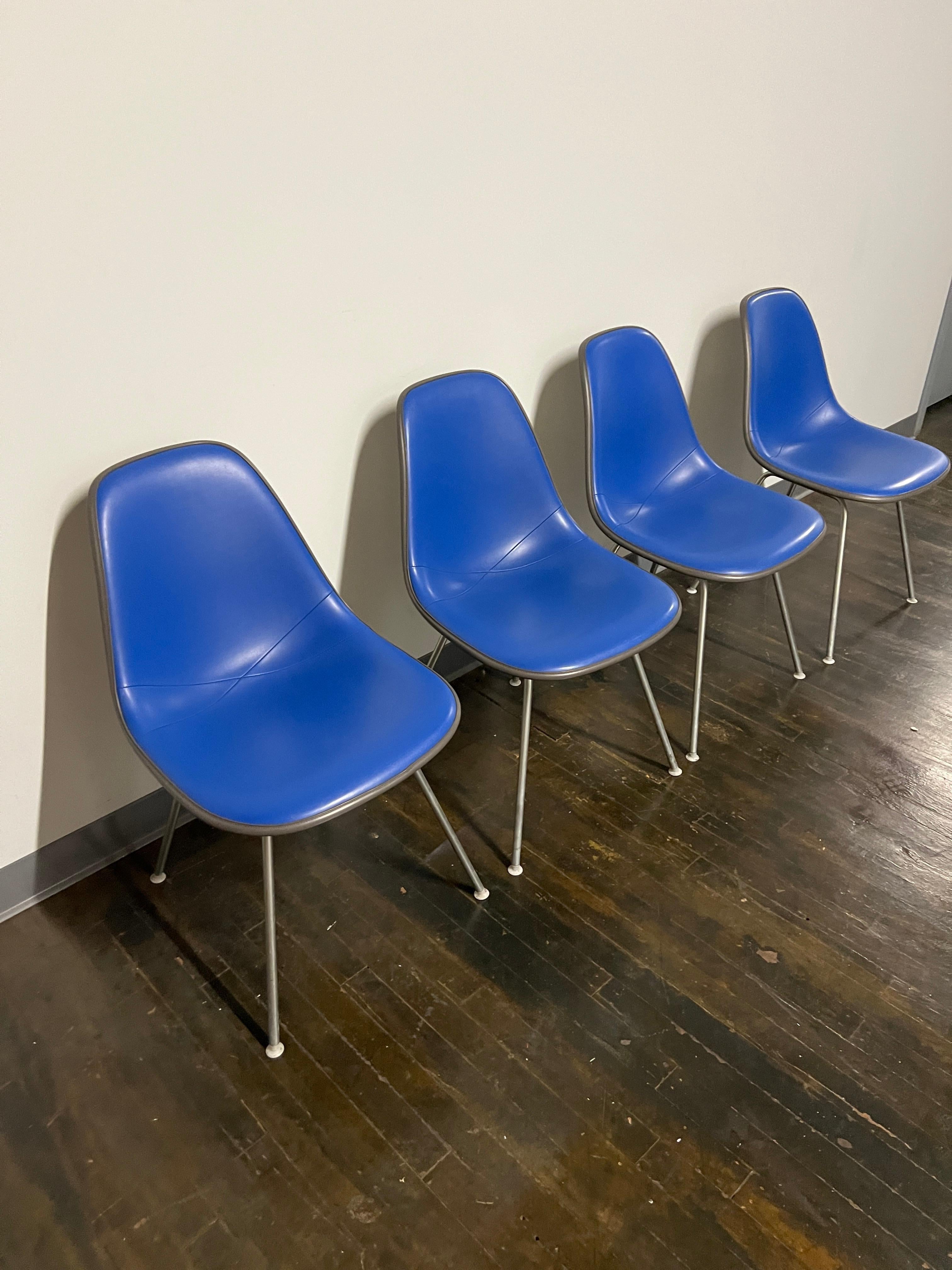 Satz von 4 sanft gebrauchten Vintage Eames Vinyl DSX Stühlen mit blauen Vinylsitzen (eine sehr helle - fast elektrisch blaue Polsterung).  Ursprünglich von Charles und Ray Eames in den 1950er Jahren entworfen.  

Der Eames DSX Stuhl ist ein