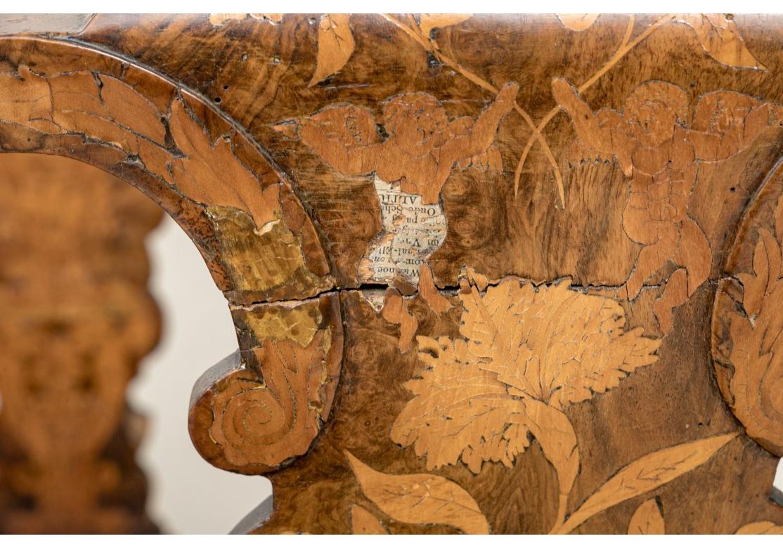 Ensemble de quatre chaises d'appoint en marqueterie de style baroque hollandais avec des sièges en cuir noir. Les chaises sont dotées de crêtes façonnées et incrustées au-dessus d'un dossier incrusté de motifs floraux, d'oiseaux, d'urnes et de