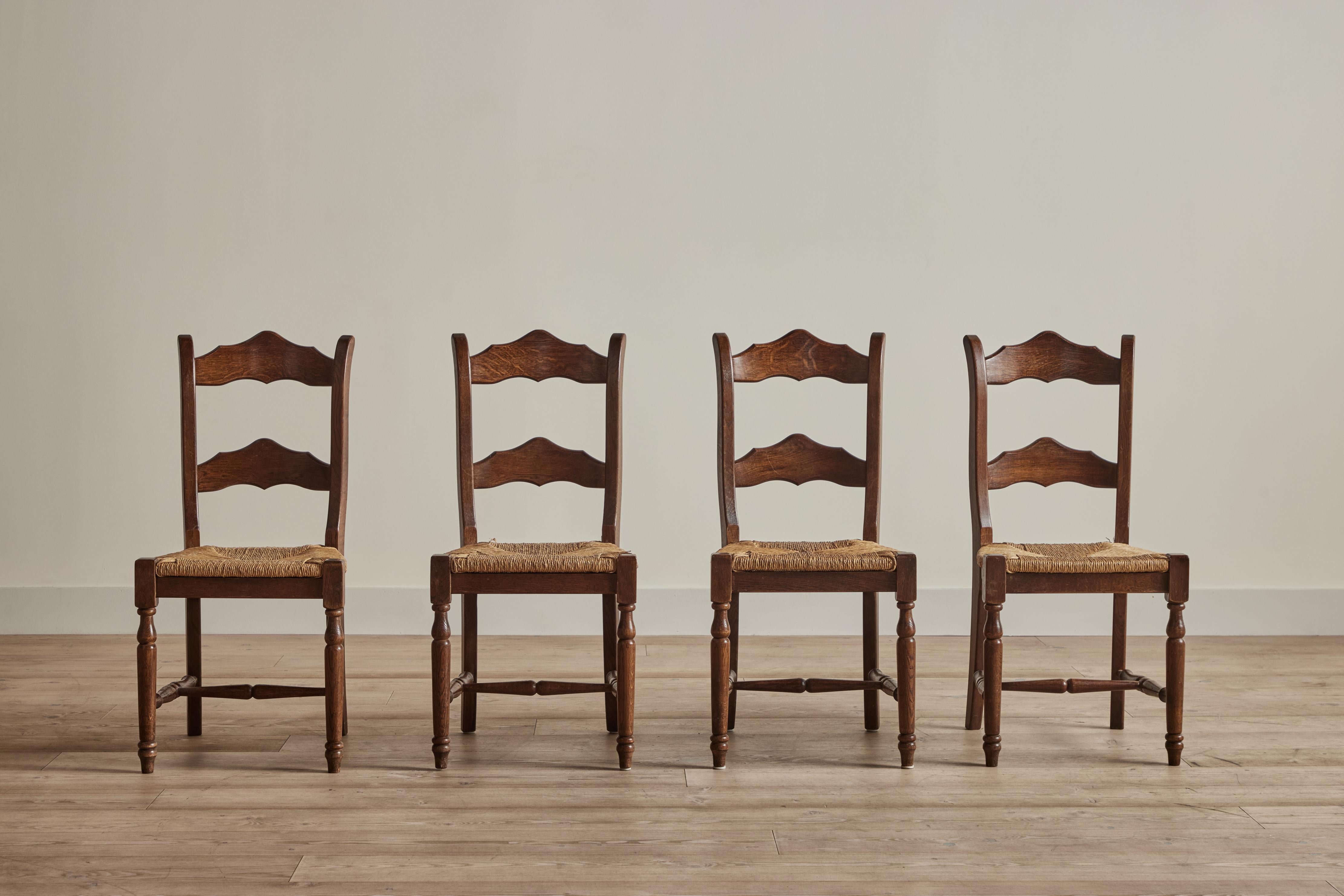 Set of four Dutch ladder back dining chairs with rush seats circa 1850. Some wear and loss on rush seats and wood frames is consistent with age and use.