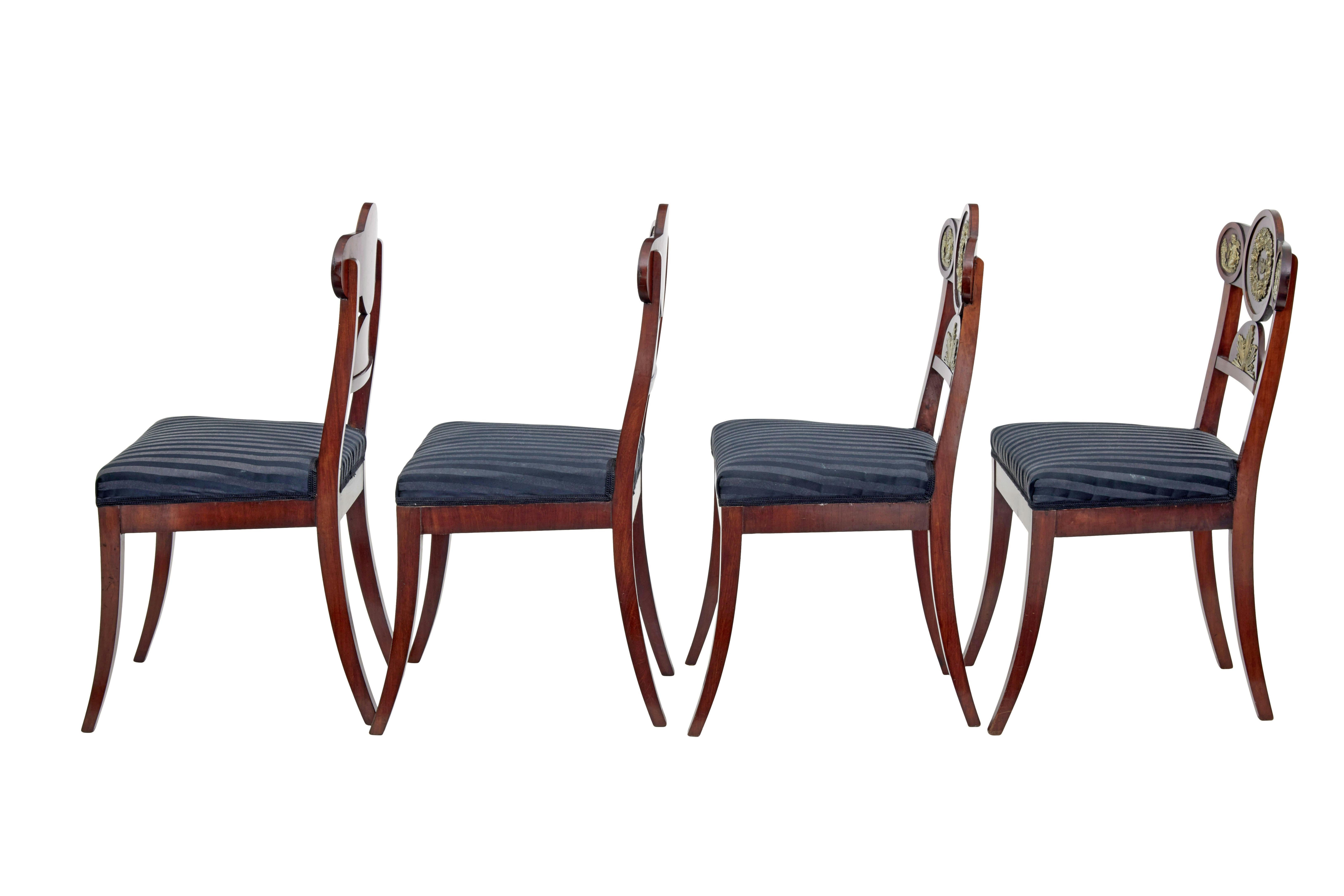 Set of 4 early 19th Swedish mahogany empire dining chairs circa 1820.

Good quality set of Karl Johan period Swedish dining chairs.   Shaped roundel backs adorned with decorative brass mounts, forming cherubs, wreathes and sun bursts.  Standing on