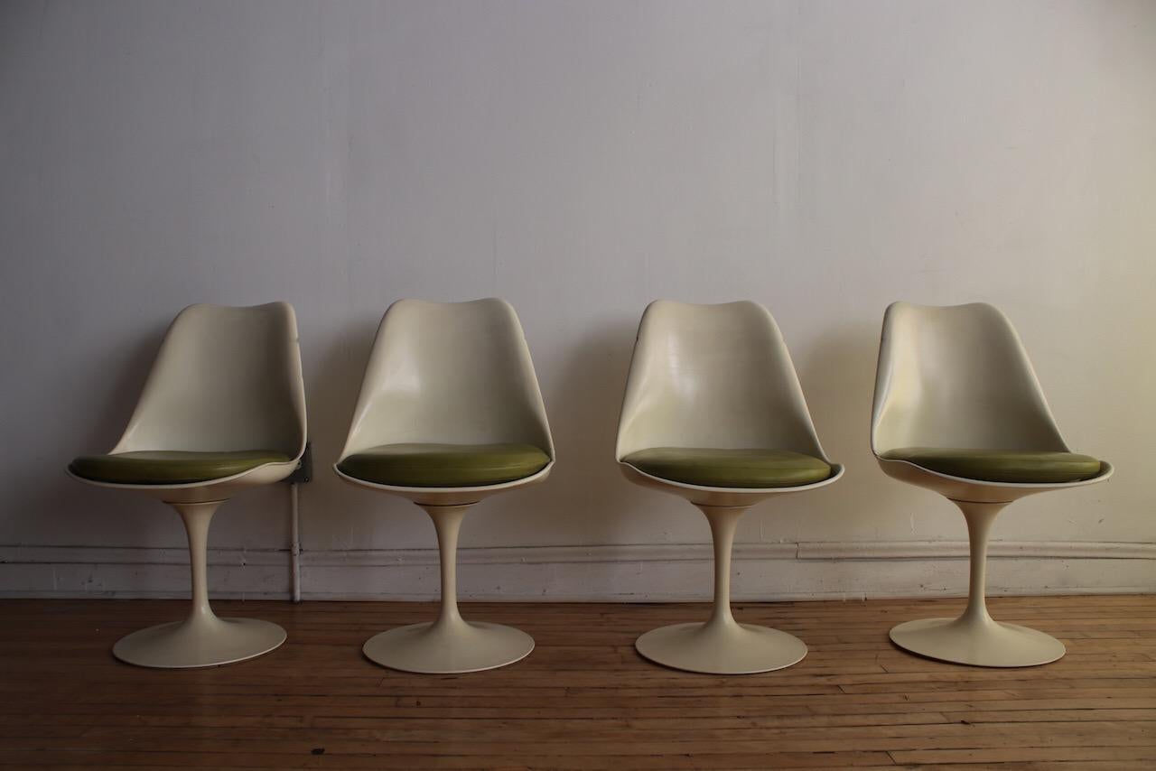 Set of four Mid-Century Modern white Tulip swivel dining chairs. 
Designed by Eero Saarinen for Knoll International. 
Original lime-avocado green vinyl upholstery.
Each sides of chairs have dents/chips from years of use.
(The family we purchased