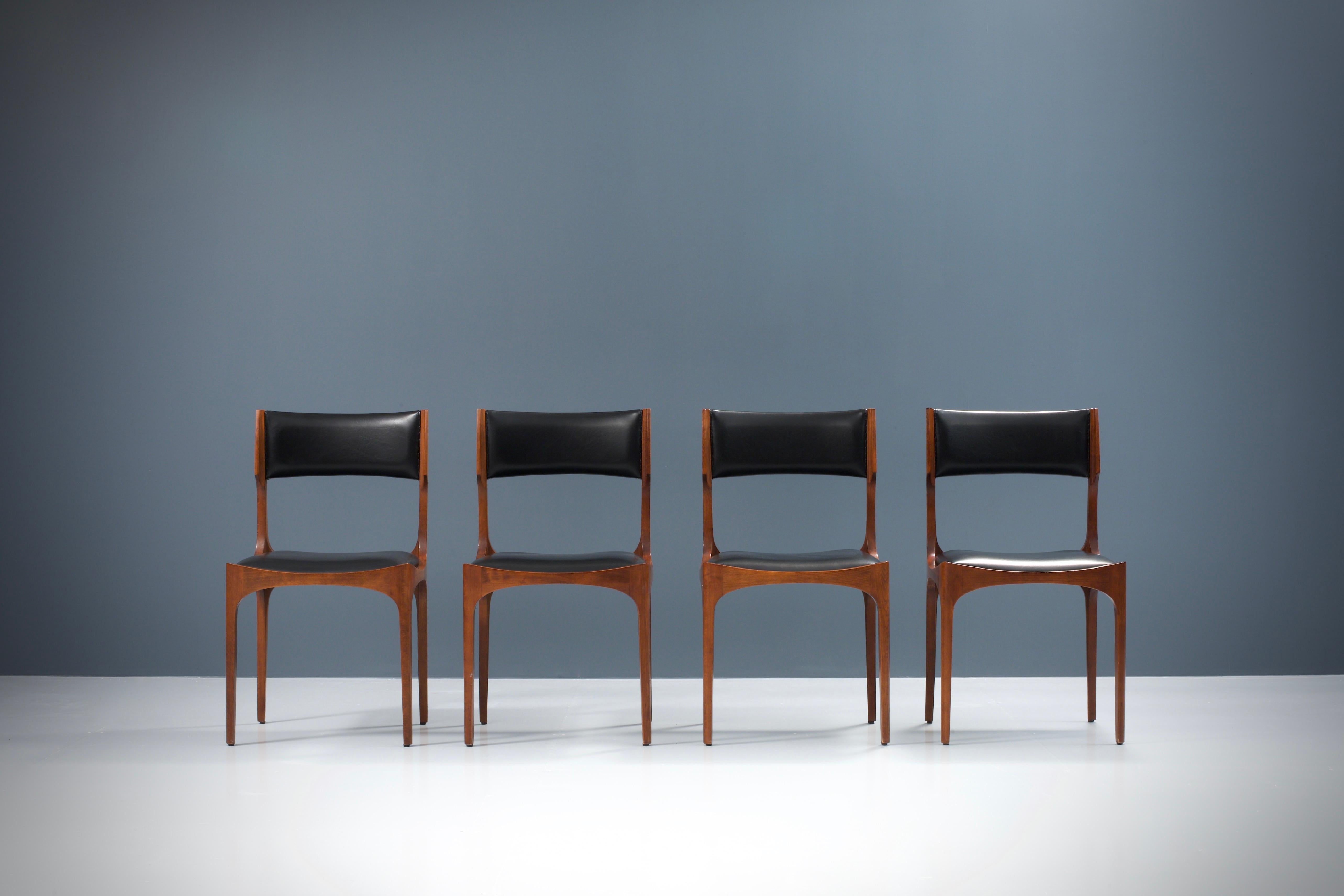 Very nicely patinated set of 4 Gibelli Chairs. The wood is really phenomenal as you can see on the pictures and contrasts very nicely with the black faux leather. Elegant chairs that are very sturdy and not wobbly at all because of the smart