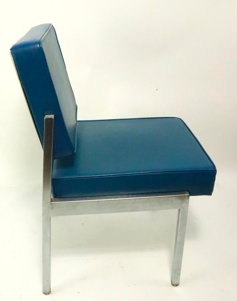 Set of four dining height chairs by EMECO having polished steel frames with blue vinyl seats and backrests. These chairs are built to commercial standards and will stand up to heavy use. Stylish modern design, manufactured by high end maker EMECO,