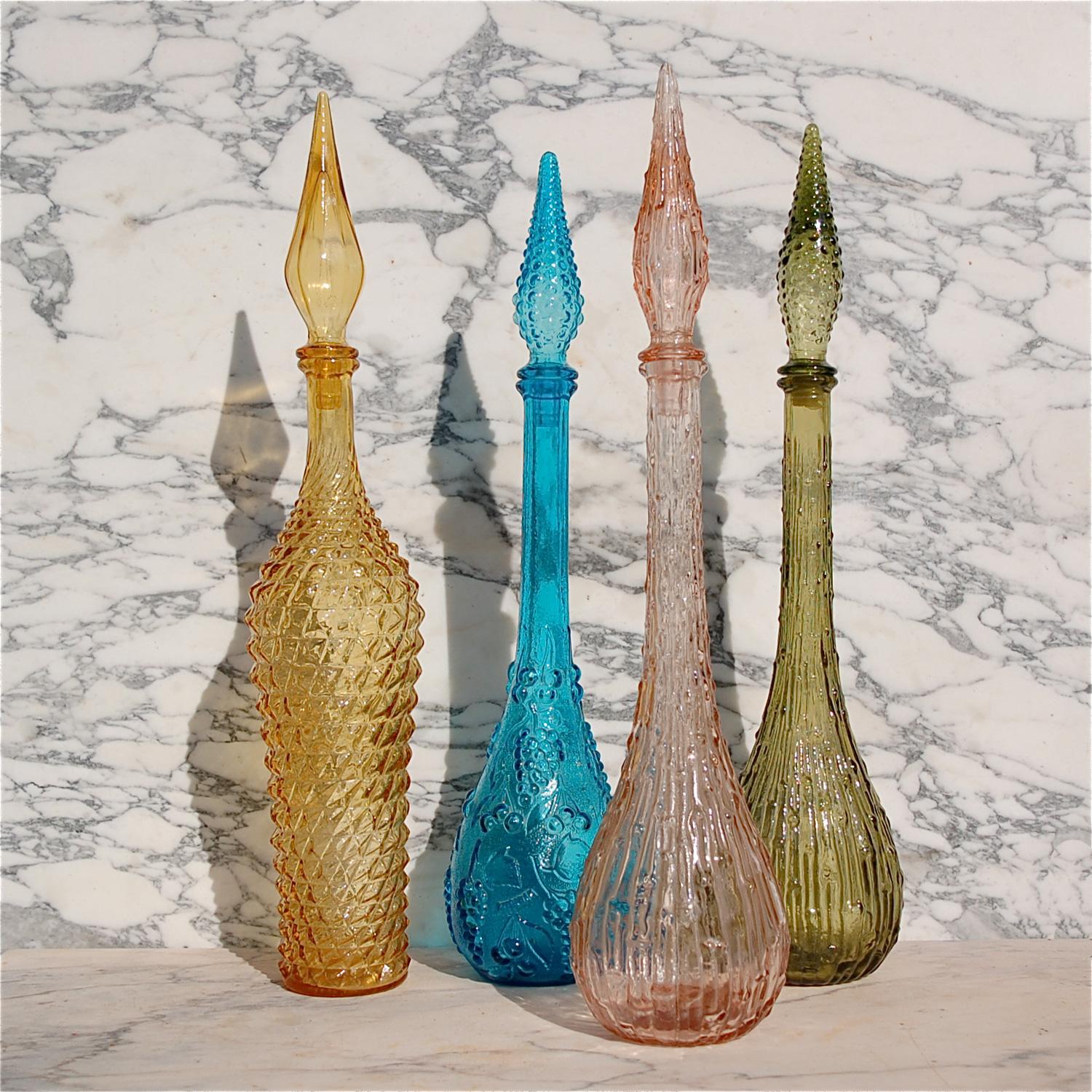 A collection of four Italian decanter bottles with stoppers, dating back to mid-20th century. This set includes different designs of which the pink and green are most similar. The common thread is the textured outer surface, which makes them very
