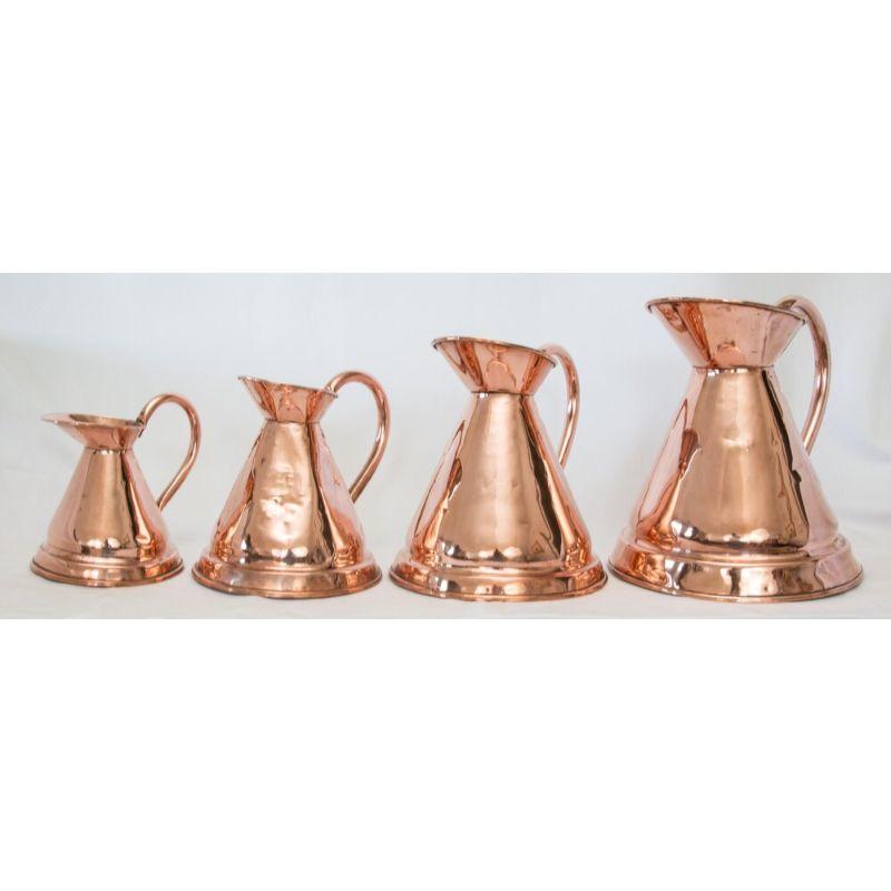 A superb set of four English solid copper haystack pitchers or jugs, circa 1900. These fine pitchers were originally used for measuring ale and they are hand forged with a lovely patina. They would be fabulous displayed together in a kitchen or