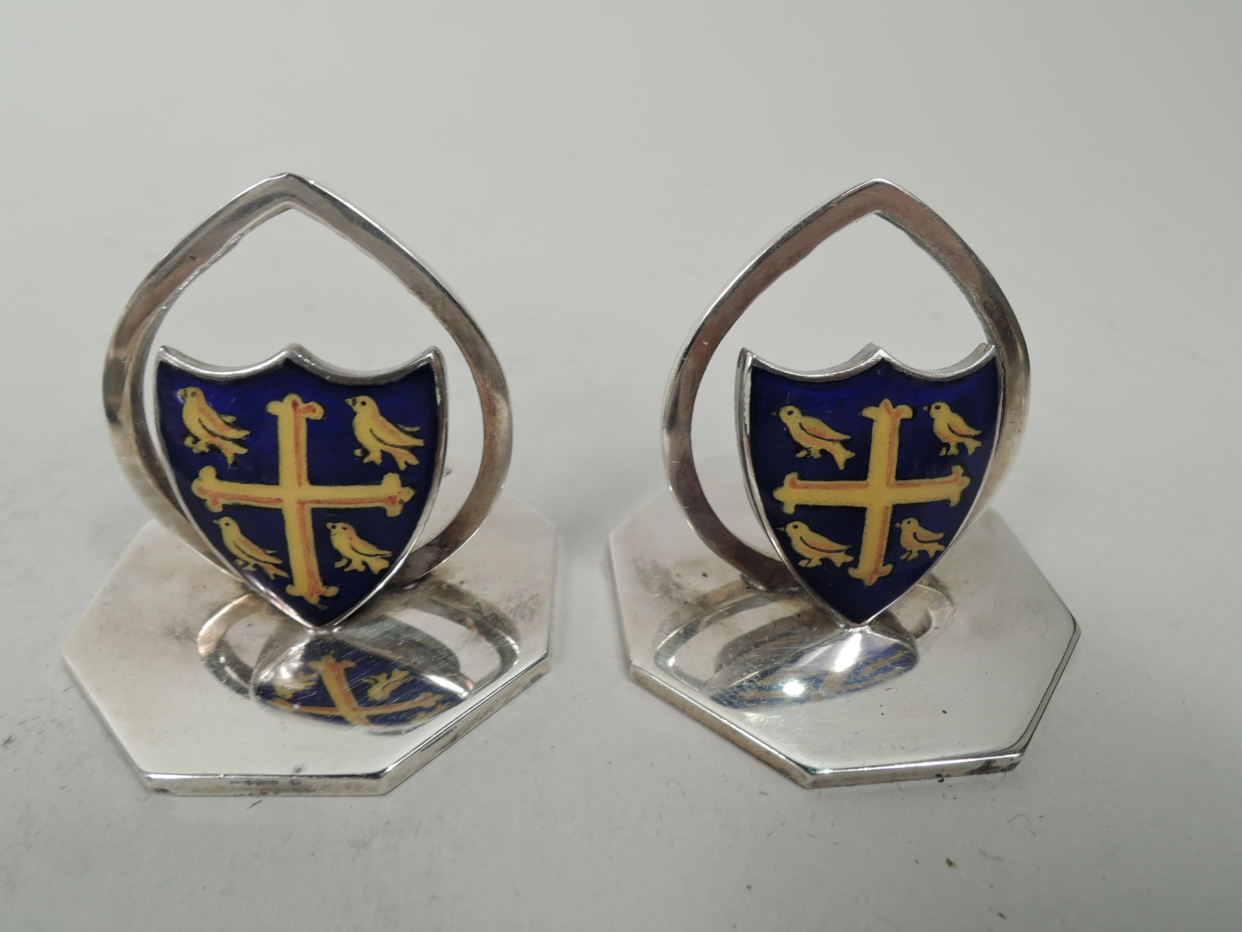 Set of 4 Edwardian sterling silver and enamel place card holders. Made by James William Benson in Birmingham, 1906 to 1908. Each: Enameled coat of arms and open oval clip mounted to flat octagonal base. Same design comprising yellow cross and birds