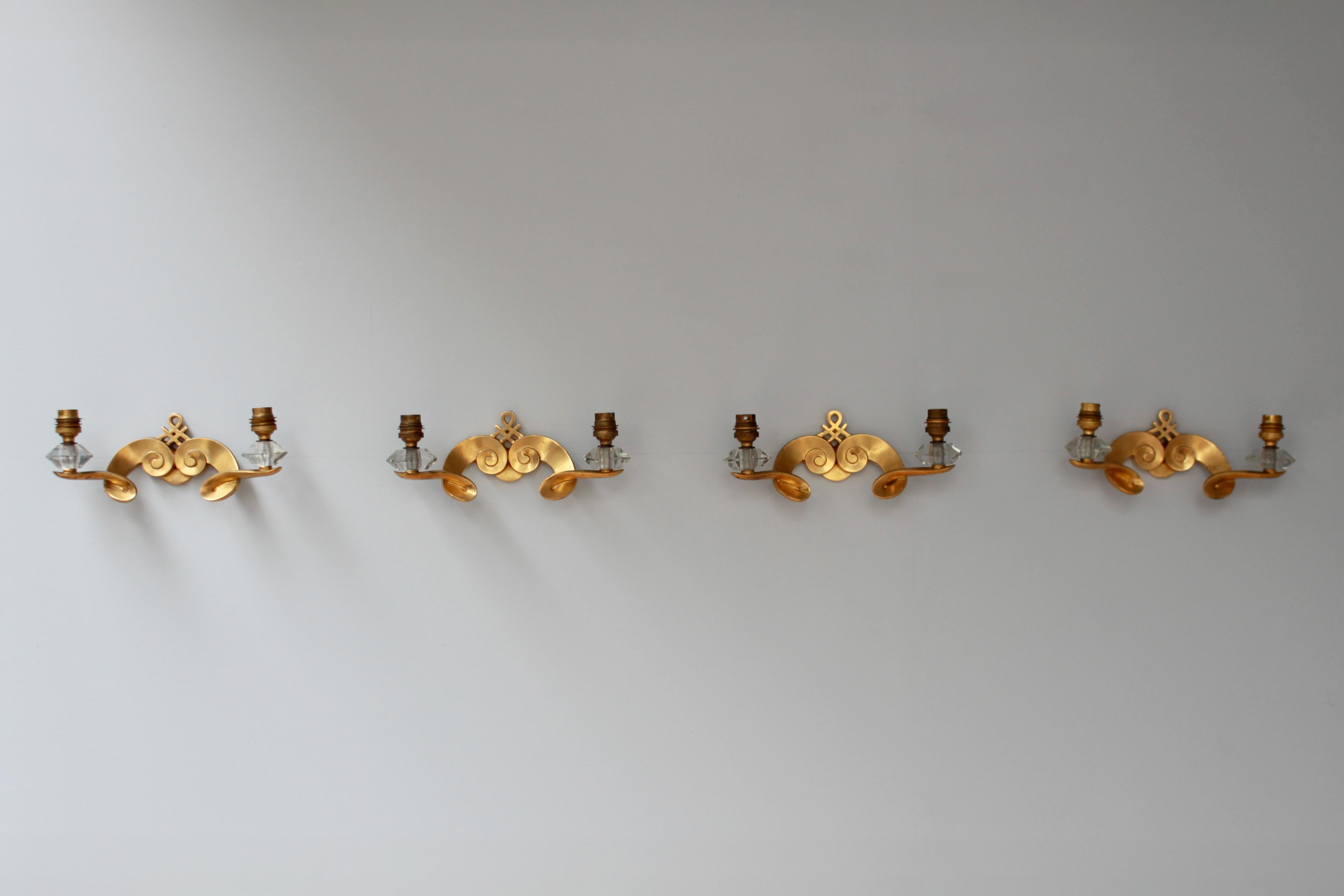 Jules Leleu - Juego de cuatro finos apliques franceses de bronce dorado de mediados de siglo, con dos brazos en espiral y detalles de cristal.  
Firmado

Las dimensiones sin sombra son:
W: 11 3/8