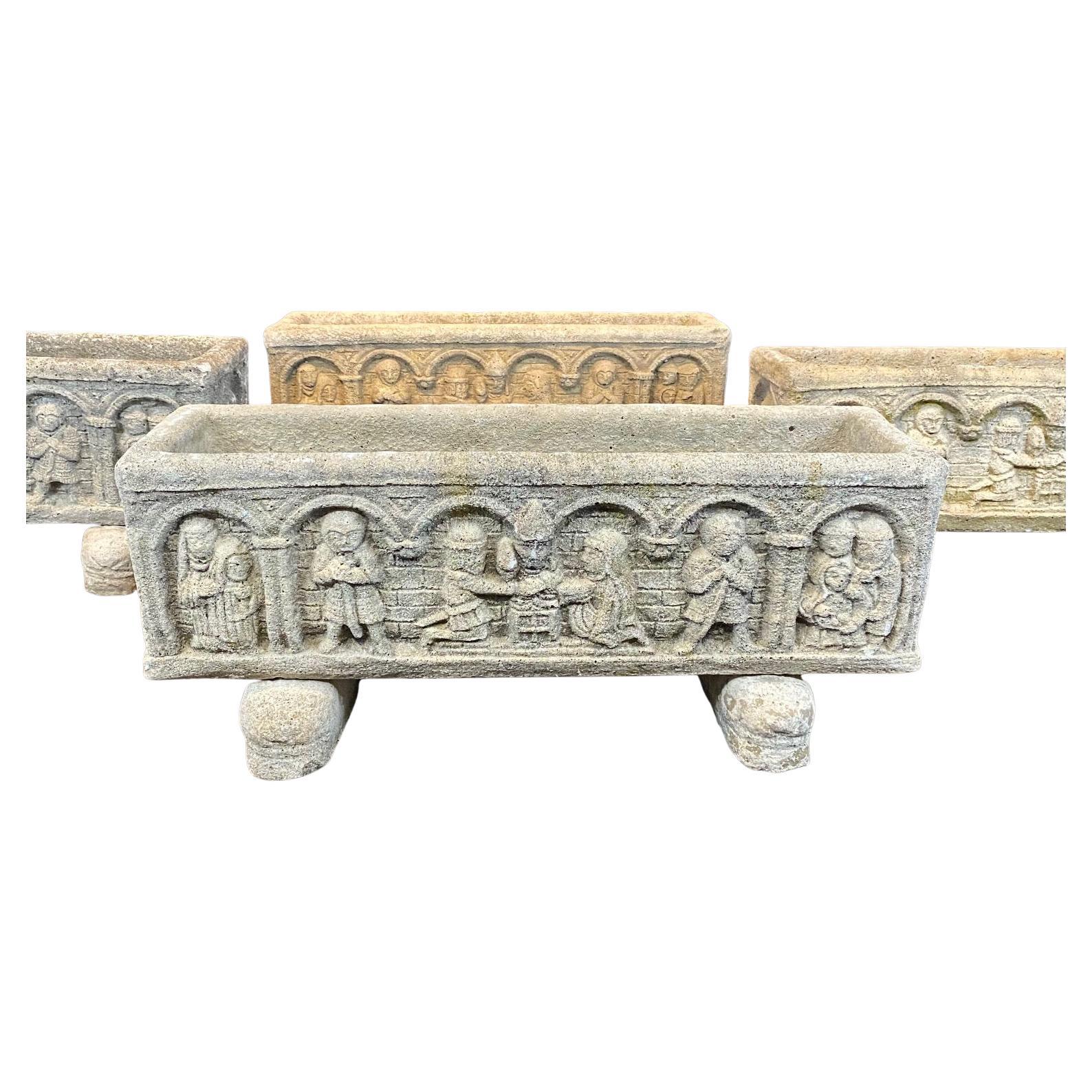 
These stone French Medieval style cast stone planters are each decorated with a horizontal frieze relief scene depicting early figures and figural scenes, as well as architectural elements, all in a medieval style, each resting on two separate
