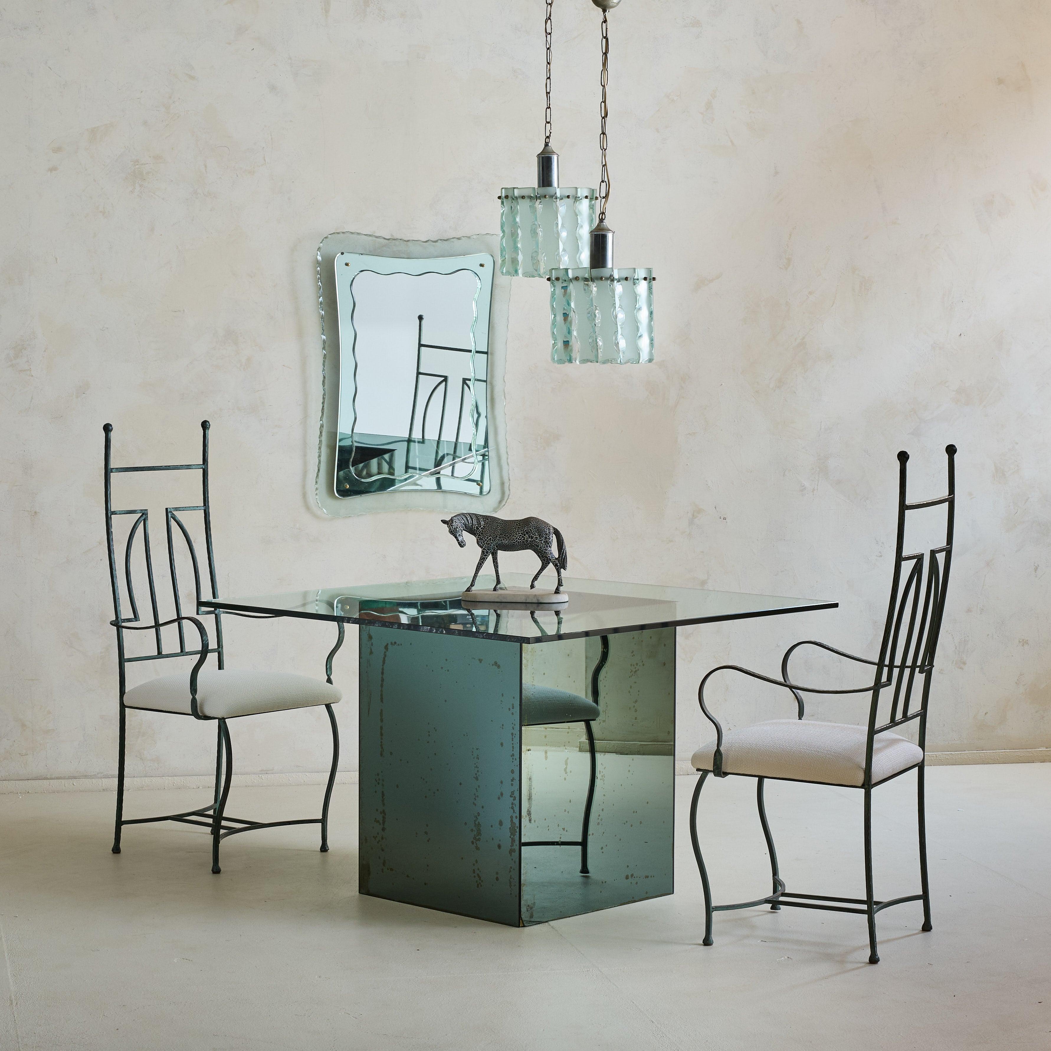 A set of four 1940s French dining chairs featuring sculptural, high-back frames in hammered iron. The rich verdigris patina enhances their character, a testament to the craftsmanship of the era. Gracefully curved arms and subtly tapered legs