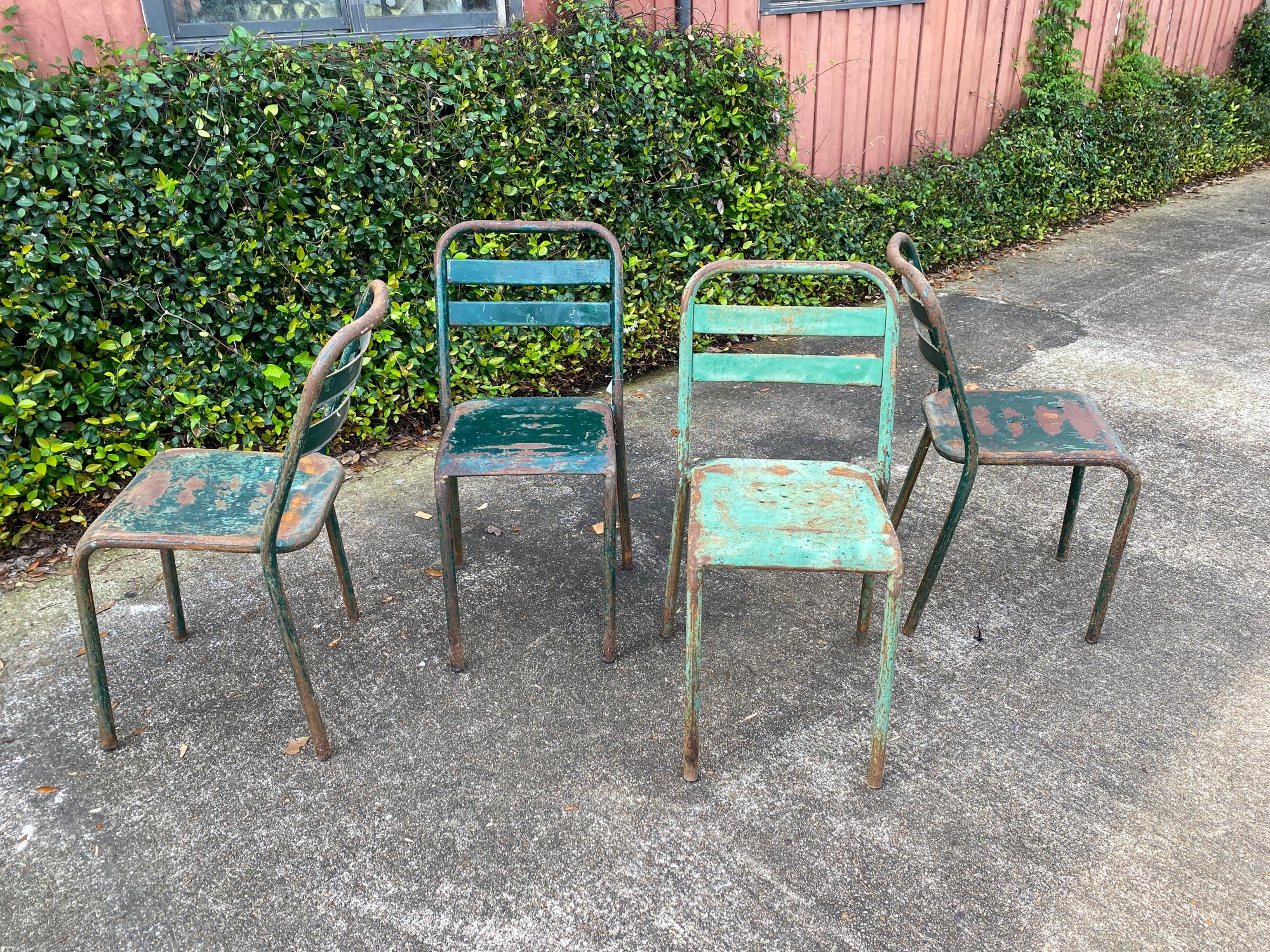 Four rustic, industrial metal chairs in a painted green finish found in France. These chairs easily stack and are all very sturdy. The painted finish does have rust and chipping and one chair is painted a lighter tone of green. The seats have