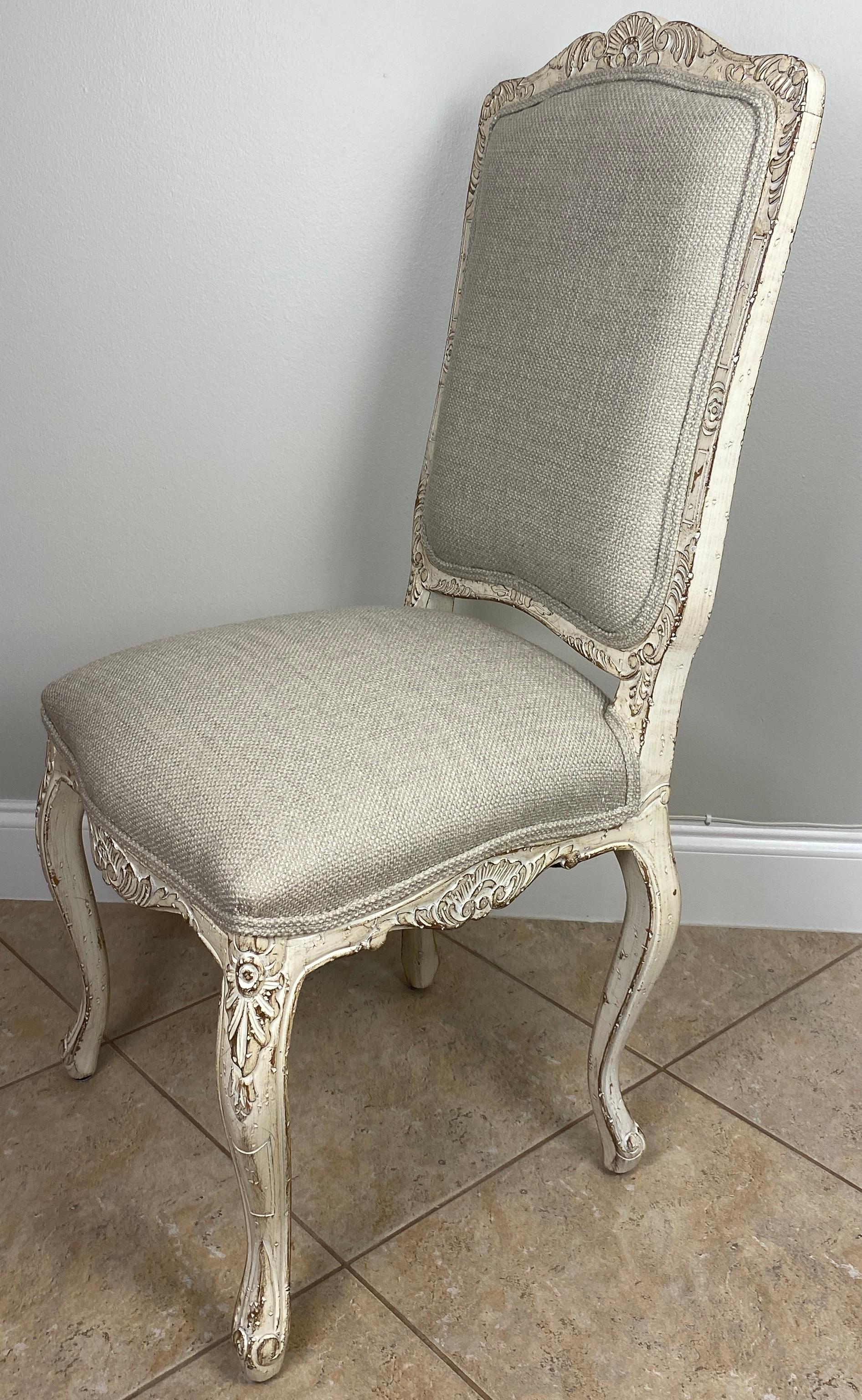 A very good quality set of four comfortable and sturdy French Louis XV style dining chairs in a pleasing antiqued beige finish. Newly reupholstered with a neutral fabric. 

The well crafted Louis XV style wood frames are hand carved. These dining