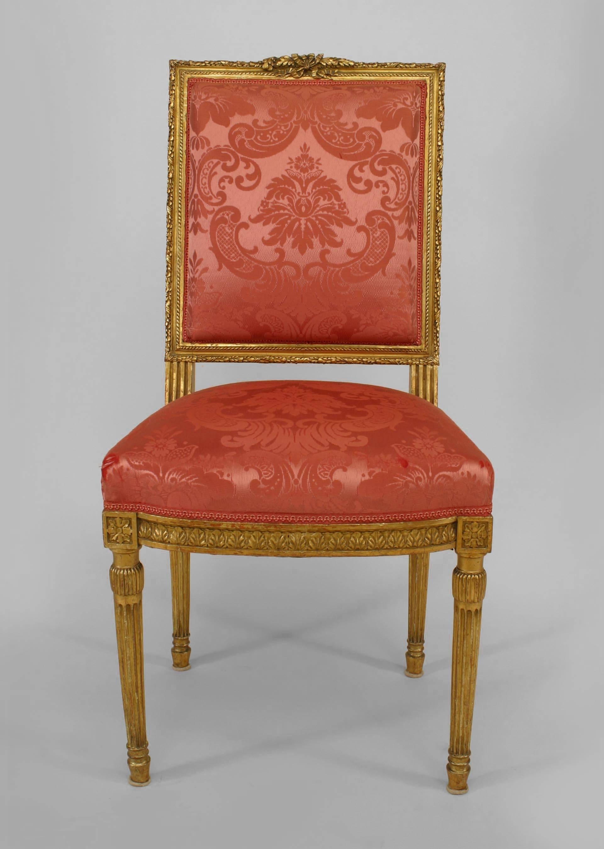 Set of four French Louis XVI style (19th Century) giltwood square back side chairs with rouge silk upholstery on fluted leg with carving on seat and back frame.

 