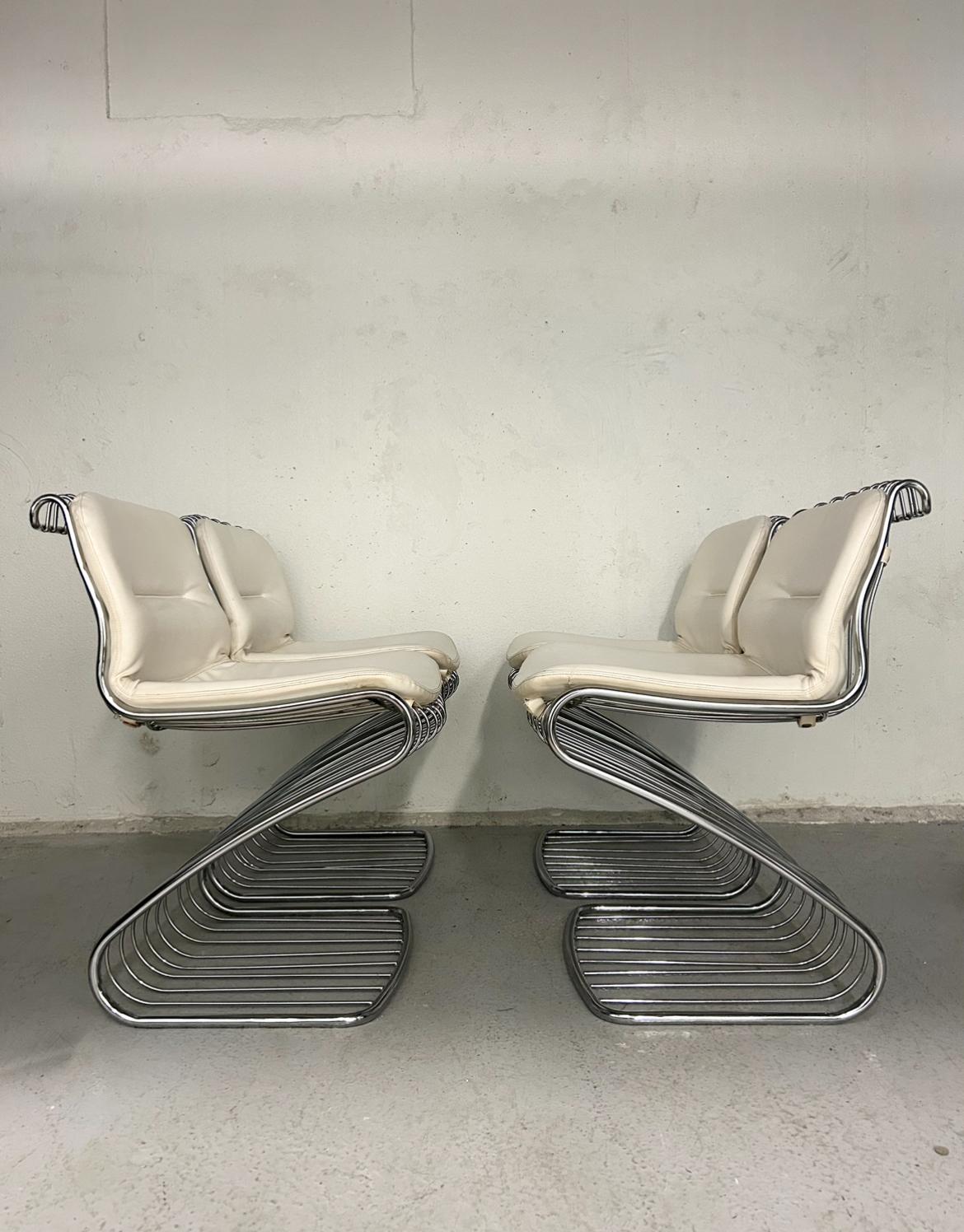 Vintage Gastone Rinaldi wire chrome cantilever chairs. Off white faux leather upholstery and chrome in very good condition. No rust on chrome. Small marks throughout upholstery. Back of chair has wear marks from the chrome wire but not that