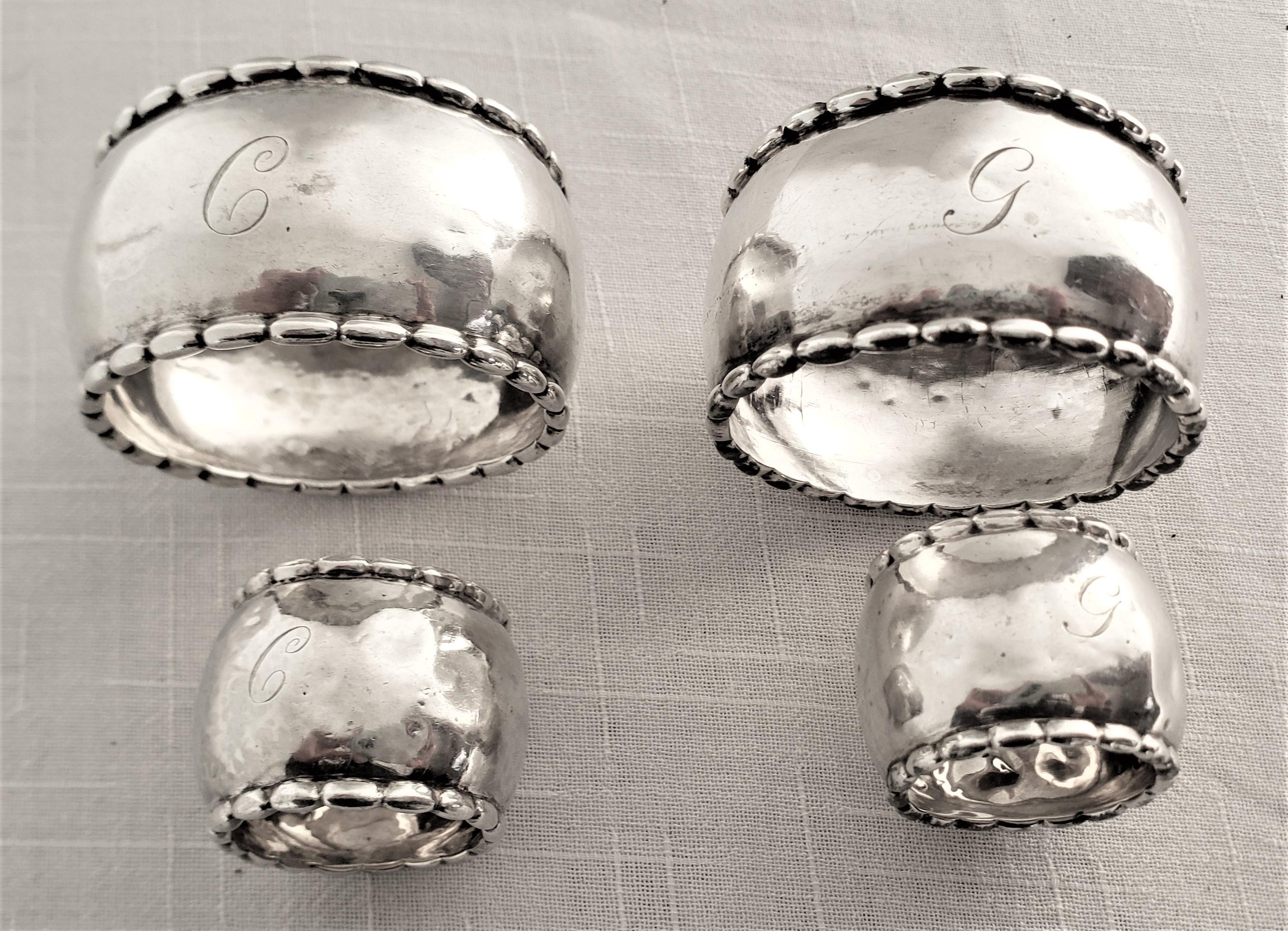 Cet ensemble de quatre ronds de serviette en argent sterling a été fabriqué par le très renommé Georg Jensen vers 1920 dans un style Art Déco. Cet ensemble de ronds de serviette est martelé à la main avec un corps convexe simple et un rebord stylisé