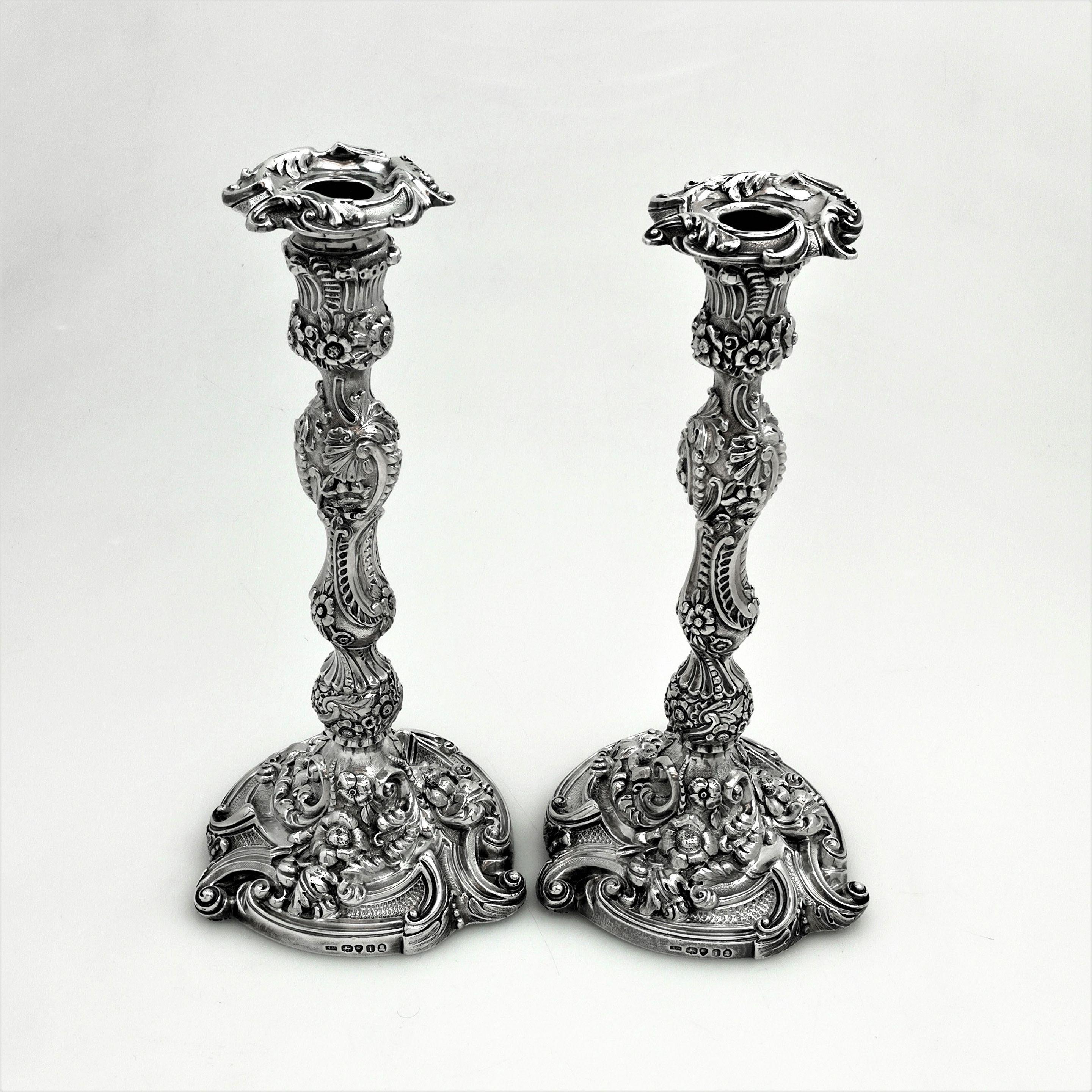 An impressive set of 4 Georgian antique solid silver rococo revival candlesticks. This set of Georgian candlesticks are cast and feature a beautiful floral and scroll design on the spread base and shaped column. The pattern, especially on the base,