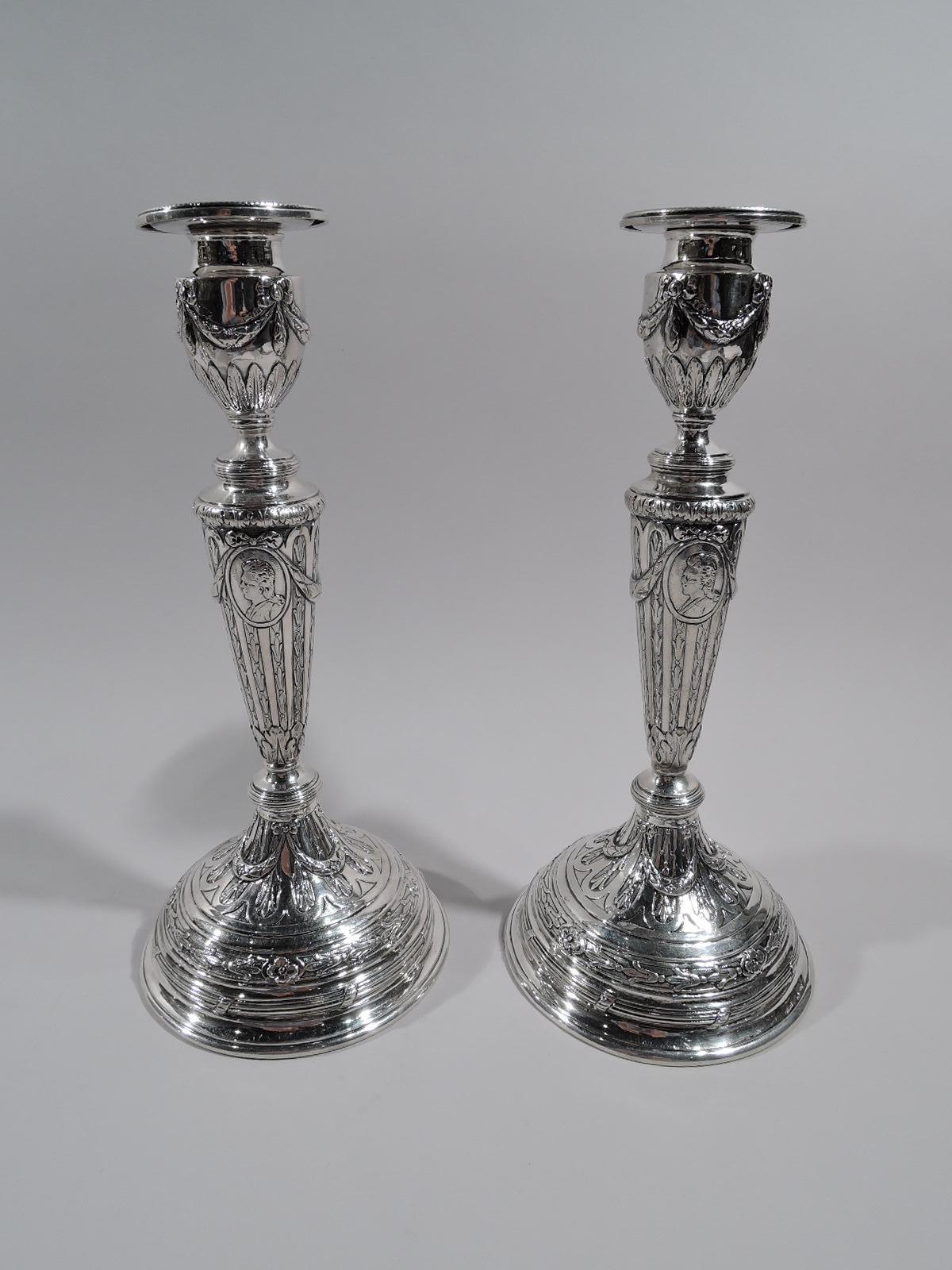 Set of 4 German Rococo 800 silver candlesticks, circa 1900. Each: tapering columnar shaft on knopped and domed foot. Urn socket with detachable bobeche. Raised ornament: gadroons inset with stylized flowers, foliage, bow-tied swags, and frames with