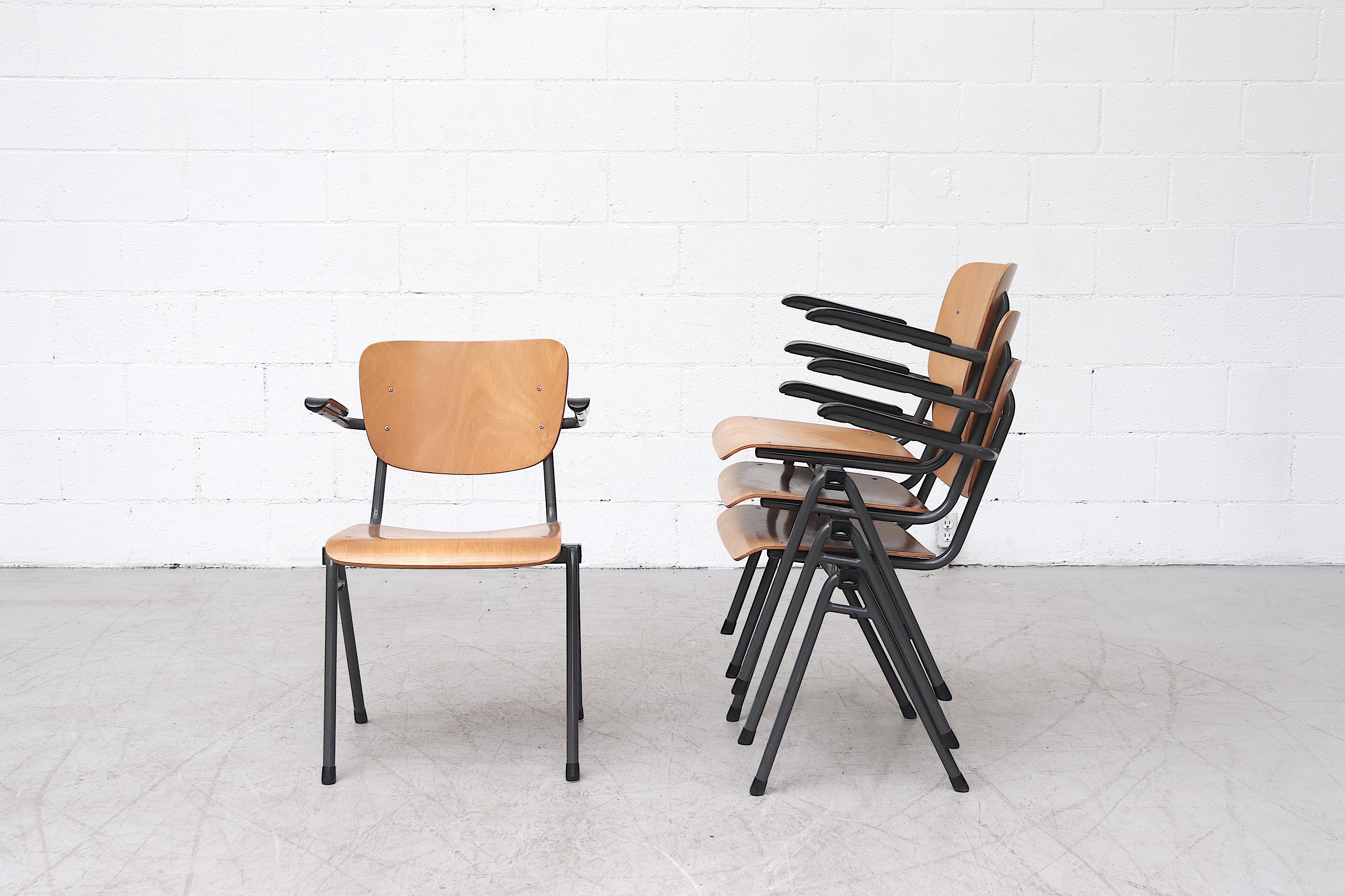 Set di quattro sedie da scuola industriali impilabili con braccioli in bachelite, struttura in metallo smaltato grigio e sedute in compensato biondo. In condizioni originali, con qualche segno di usura dovuto all'età e all'uso. Prezzo fisso.
