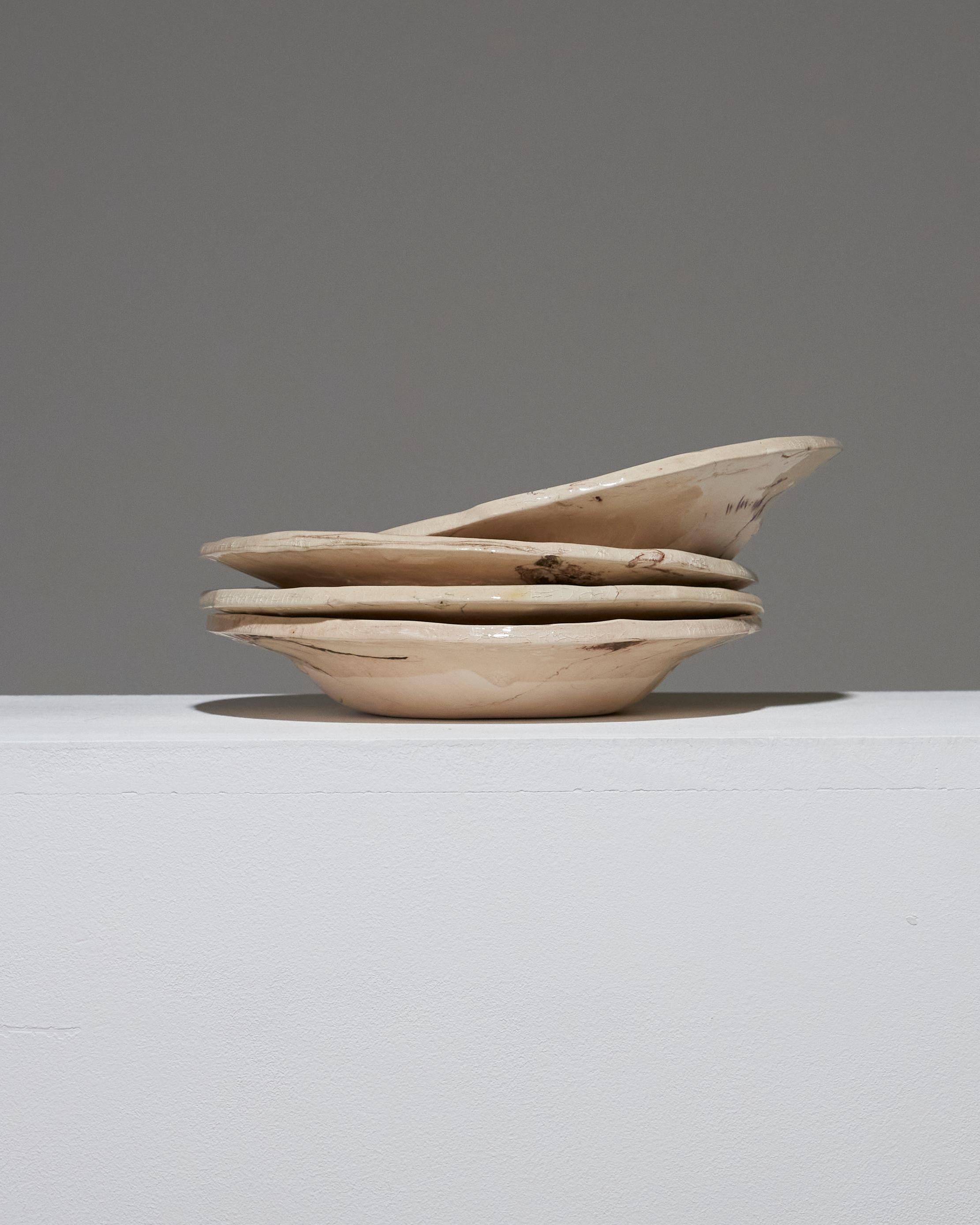 Lot de 4 assiettes creuses en céramique émaillée beige à effet marbré, par l'artiste Suzie Lapierre d'Artistics. Chaque pièce est unique, avec des motifs et des finitions variés, mettant en valeur la nature artisanale de la création. Signé sous la