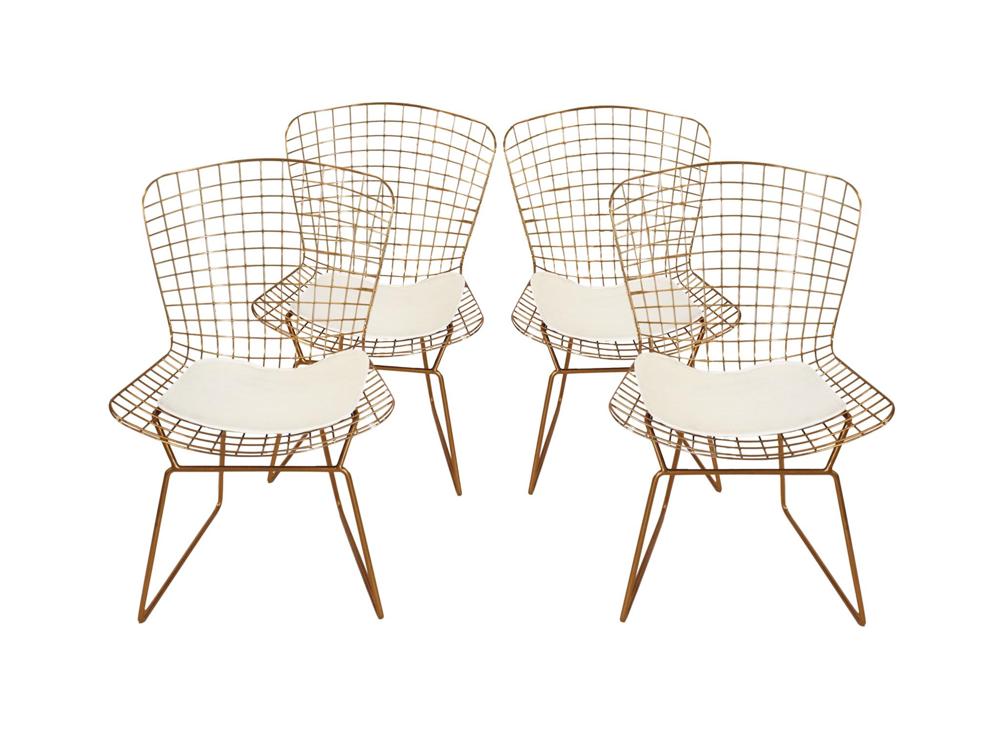 These wire chairs are designed in the iconic style of Harry Bertoia. They are chrome with a rich gold finish. Each chair has a white vinyl seating pad.

Dimensions:
20 in. width
17 in. depth
31.75 in. height

Condition notes:
In good