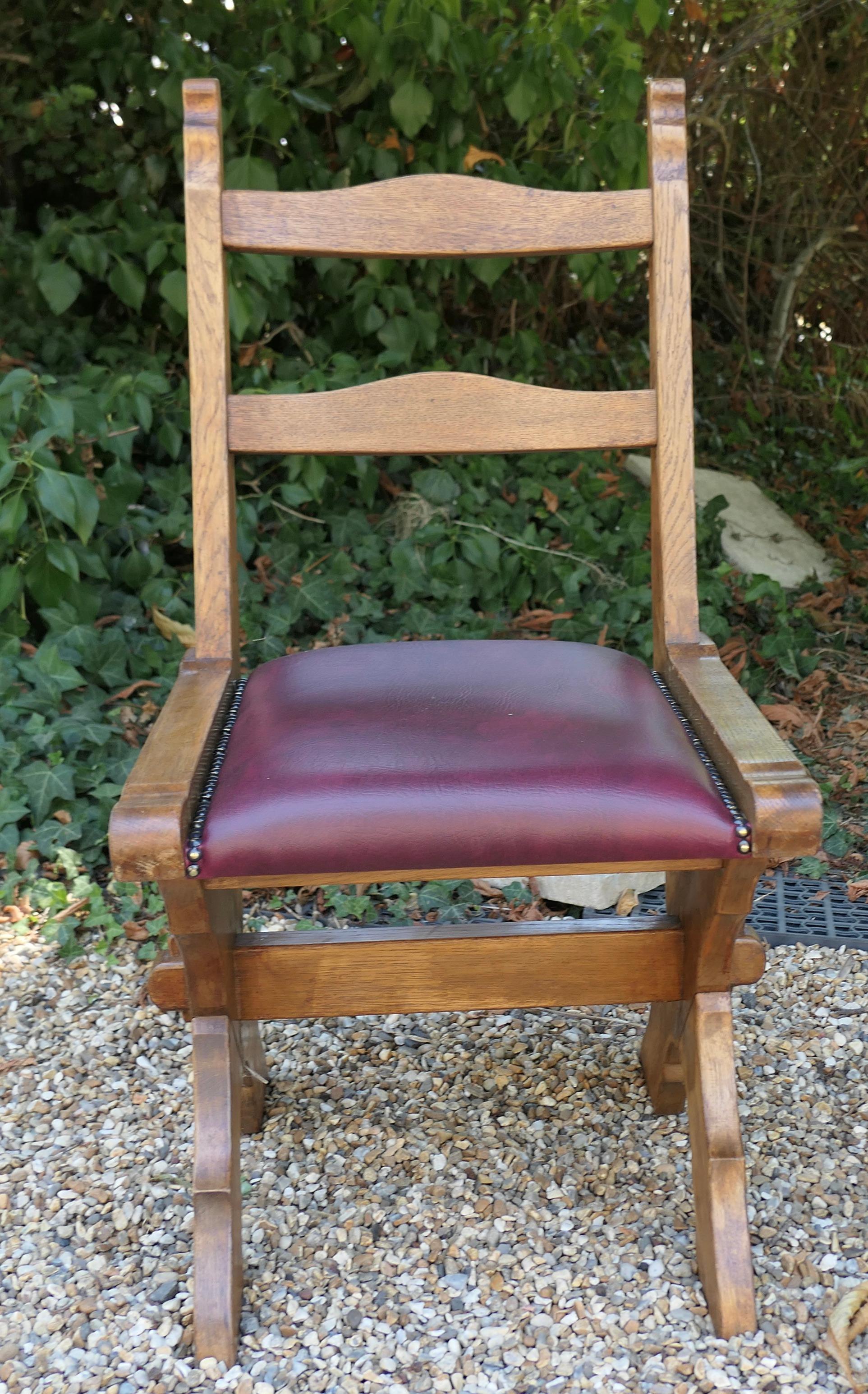 Set of 4 Golden Oak Arts and Crafts X frame refectory dining chairs

These very sturdy Oak chairs are set on X Framed Legs, the seats have been covered with Burgundy Simulated Leather and Brass studs.
Attractive and stylish all in good condition