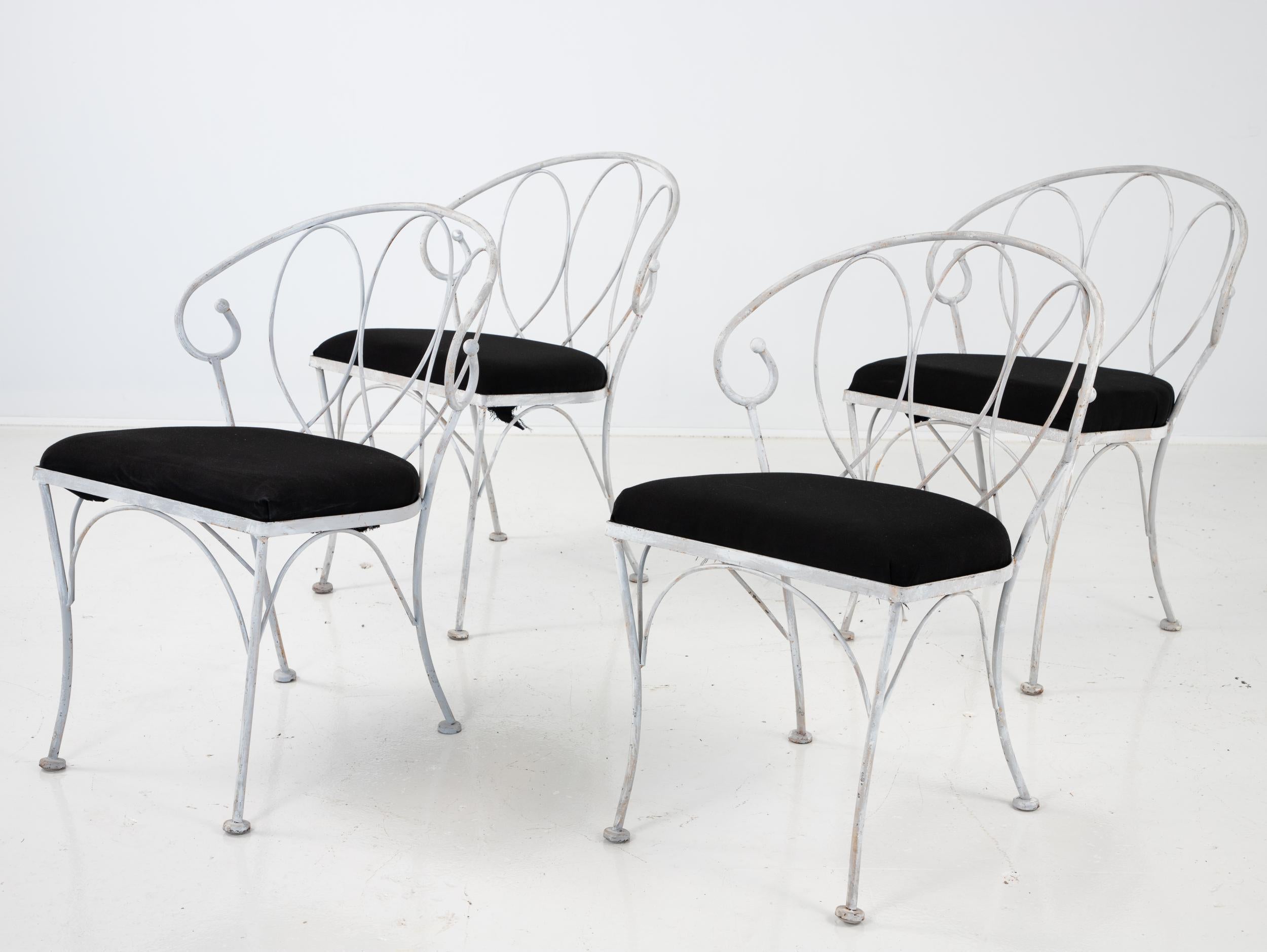 A set of four gray painted loop-style garden dining chairs with black cushions. Seat dimensions are 17