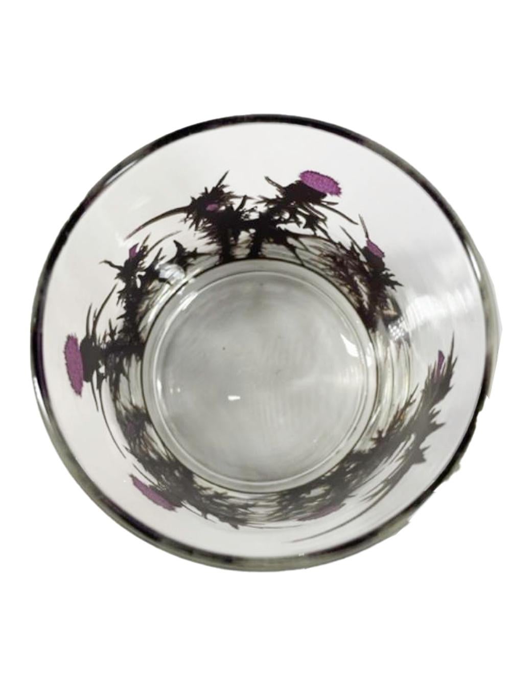 Set of four rocks glasses designed by Gregory Duncan for West Verginia Glass having thistles in raised translucent purple enamel and with 22 karat gold covering the enamel except for the flower top, leaving the enamel only visible on the interior of