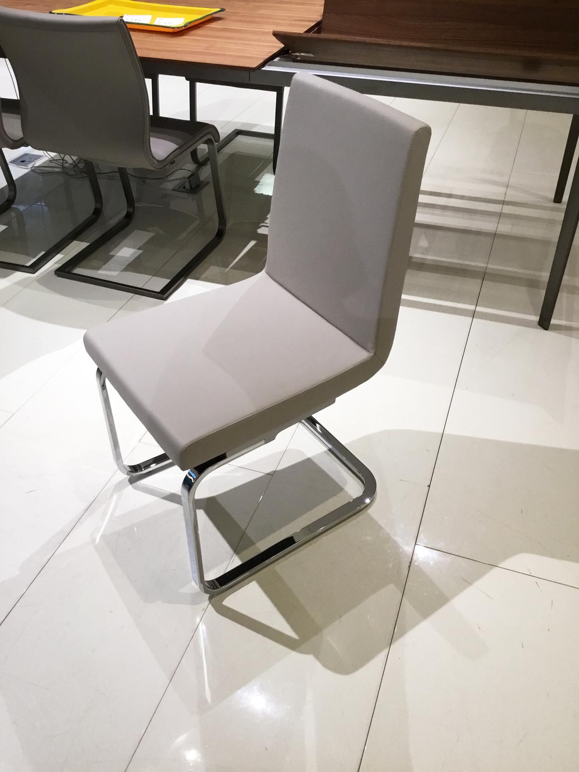 Set of four grey beige leather dining chairs with a cantilevered rectangular tubed base in polished chrome.

Showroom display chairs, two of which were manufactured in 2017 and the other two manufactured in 2021. They are made up in the same