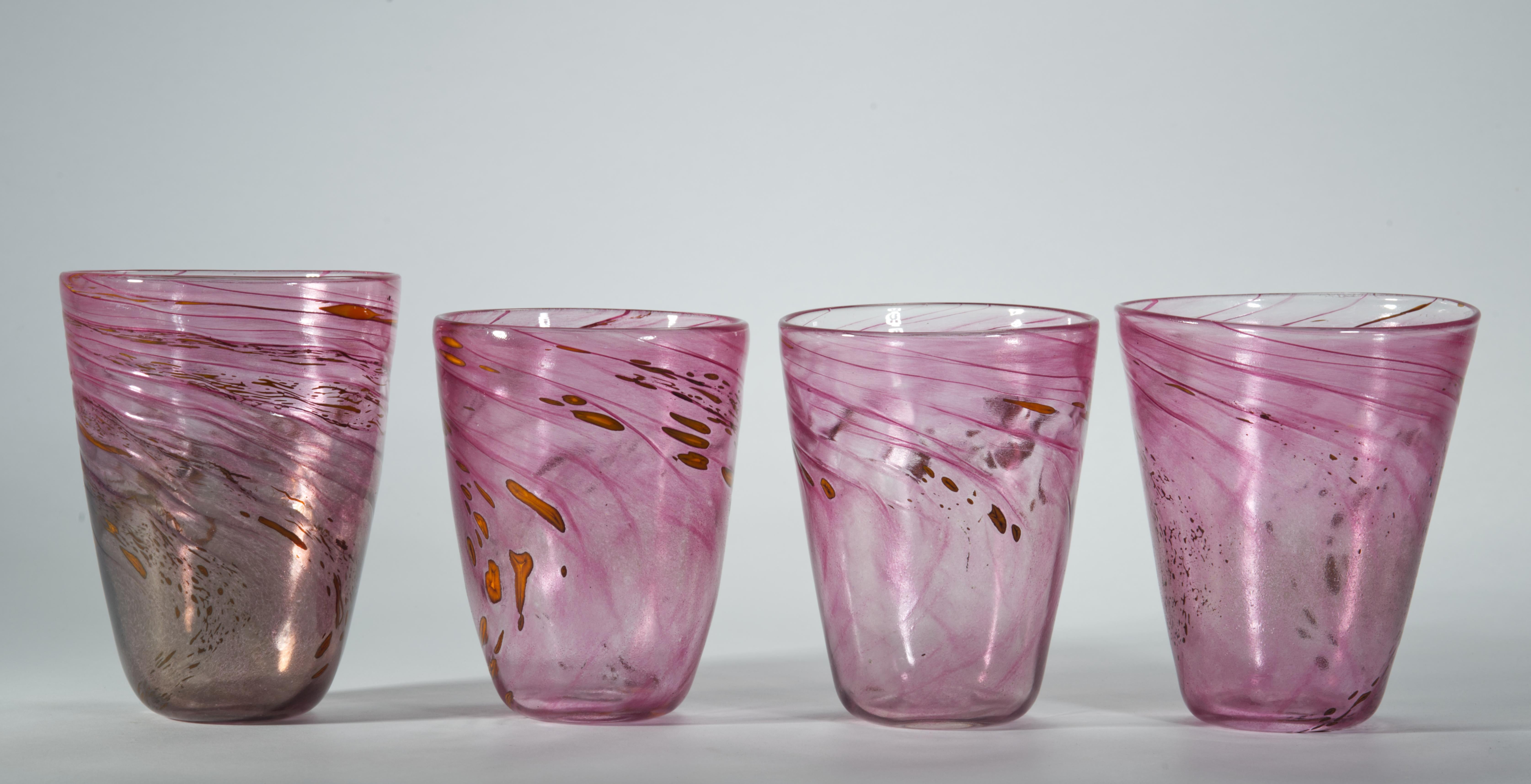 Cet ensemble de 4 gobelets ou verres vintage a été soufflé à la main dans un verre rose semi-transparent avec un motif abstrait et fluide de verre coloré fusionné, créant une composition dynamique et joyeuse. L'ensemble de lunettes est réalisé dans