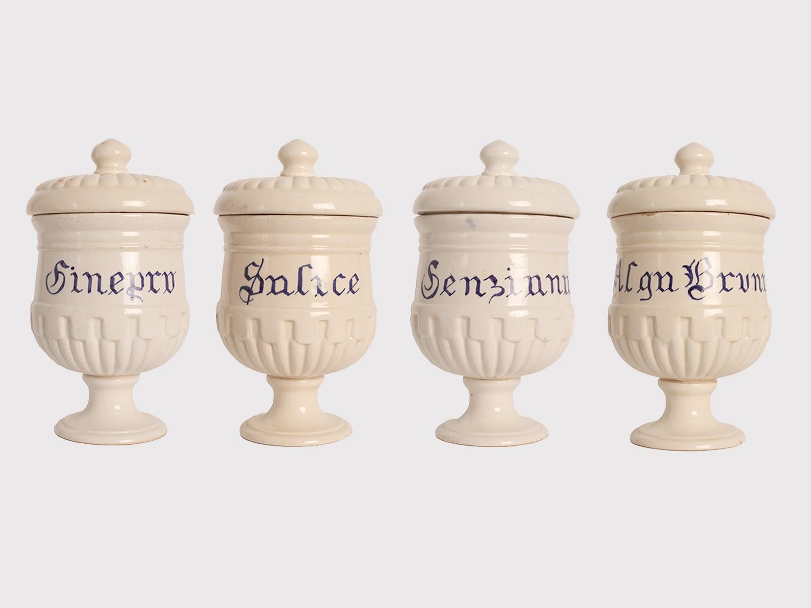 Set of 4 small jars with lid for pharmacy-herbalist's shop in white ceramic with cobalt blue inscriptions, to contain Juniper, Willow, Gentian, Brown seaweed of neoclassical taste with geometric decorations in relief. Unidentified brand. Italy circa