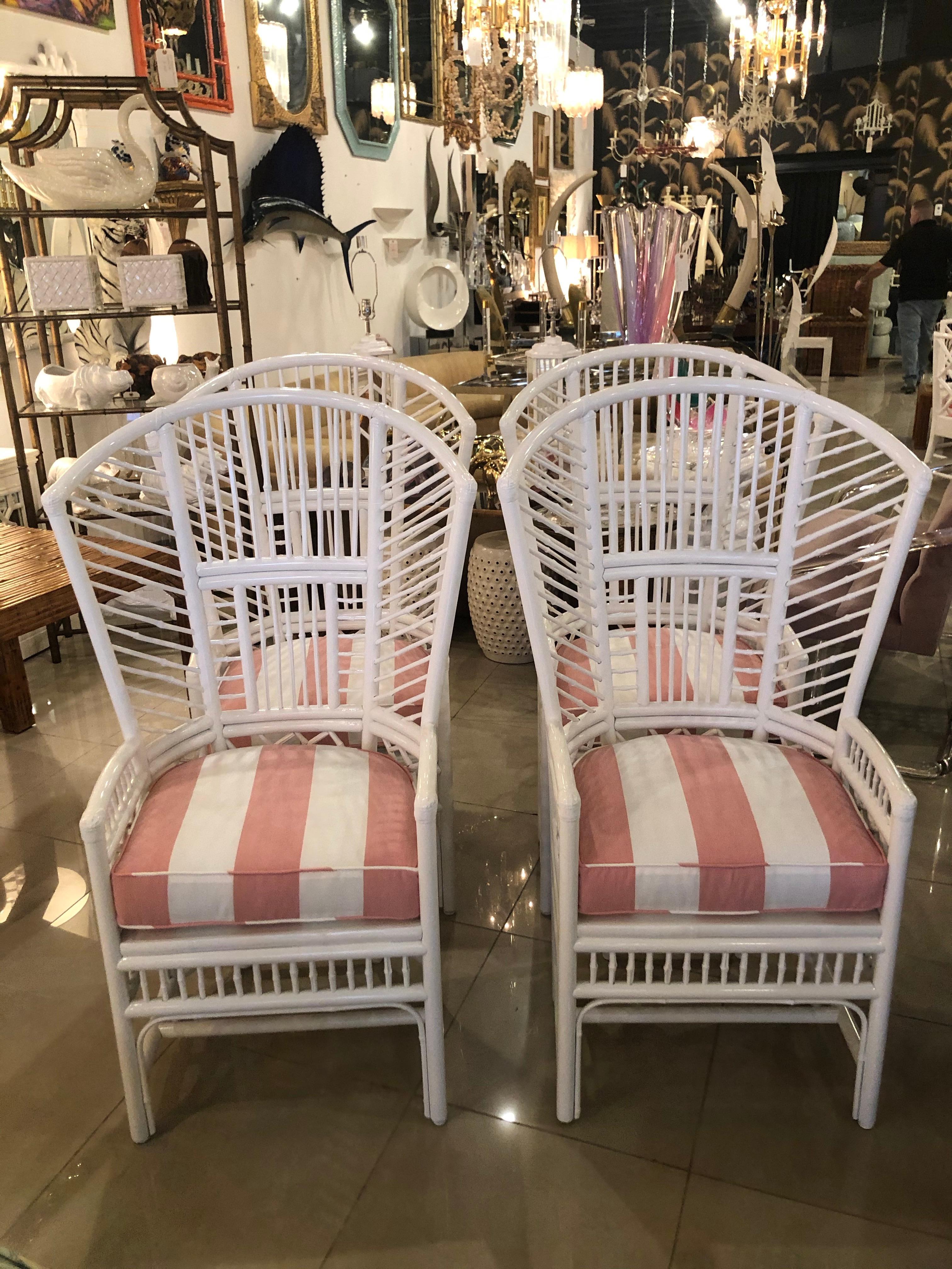 Set of 4 vintage high back rattan Brighton style dining chairs. These have been professionally lacquered white and have new coral and white stripe indoor/outdoor cushions. Cushions are removable, cane underneath has no damage.