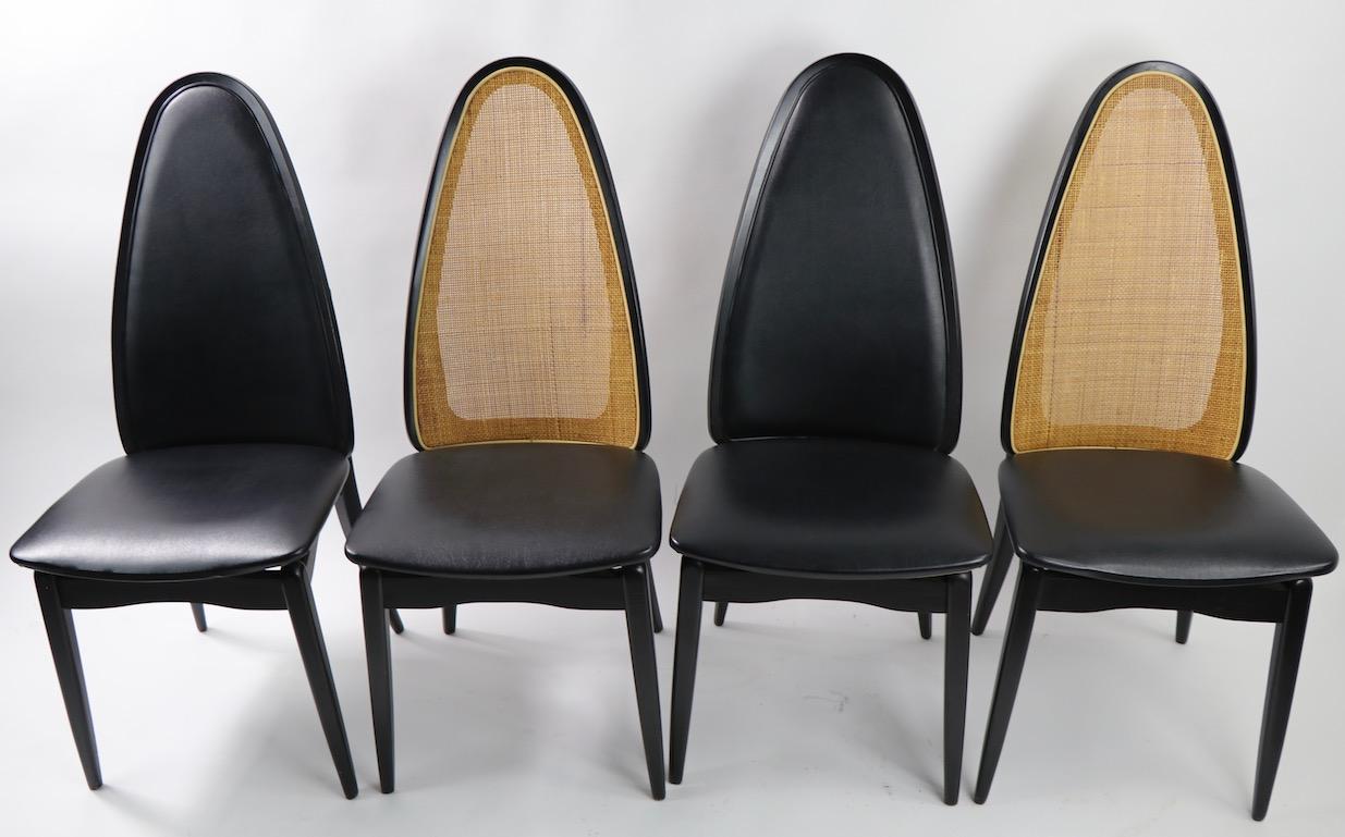 Very chic and stylish set of four high back chairs manufactured by Stackmore. This set includes two cane back and two upholstered back chairs, all having black wood frames and black vinyl seats. The chairs are in excellent original condition, clean