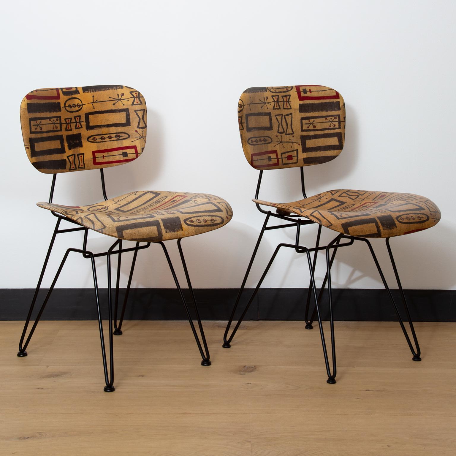 A set of 4 side/dining chairs designed by Hobart Wells for Lensol-Wells. The seat and backs feature an abstract pattern from fabric which has been encased in moulded fibreglass, with the wire metal frames made from black enamelled steel further