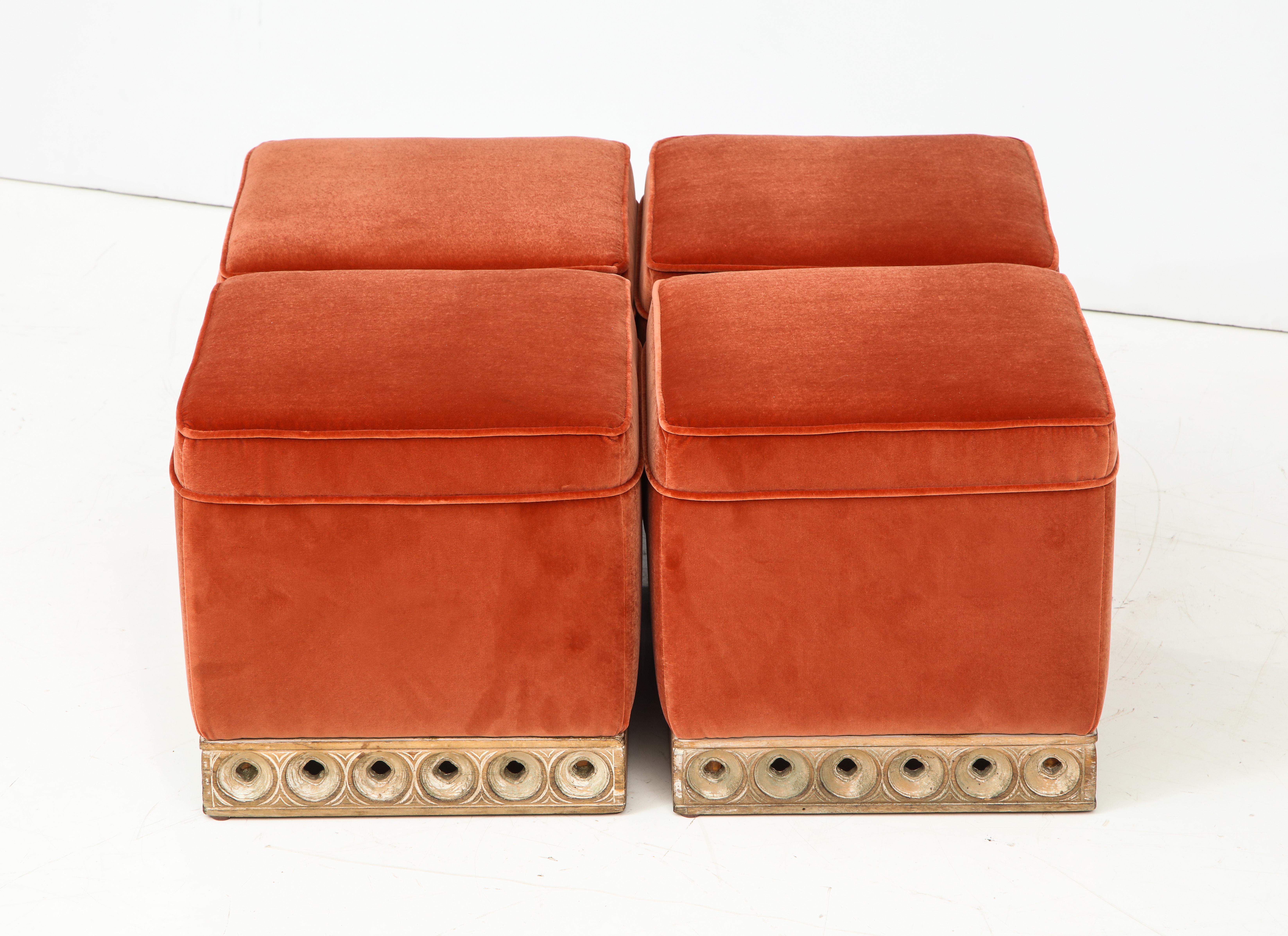 These Italian mid-century modern poufs or stools with wooden carved base are absolutely chic and versatile. A set of four which can be grouped as a single ottoman or individually. Completely restored and newly upholstered in a Vermillion or burnt