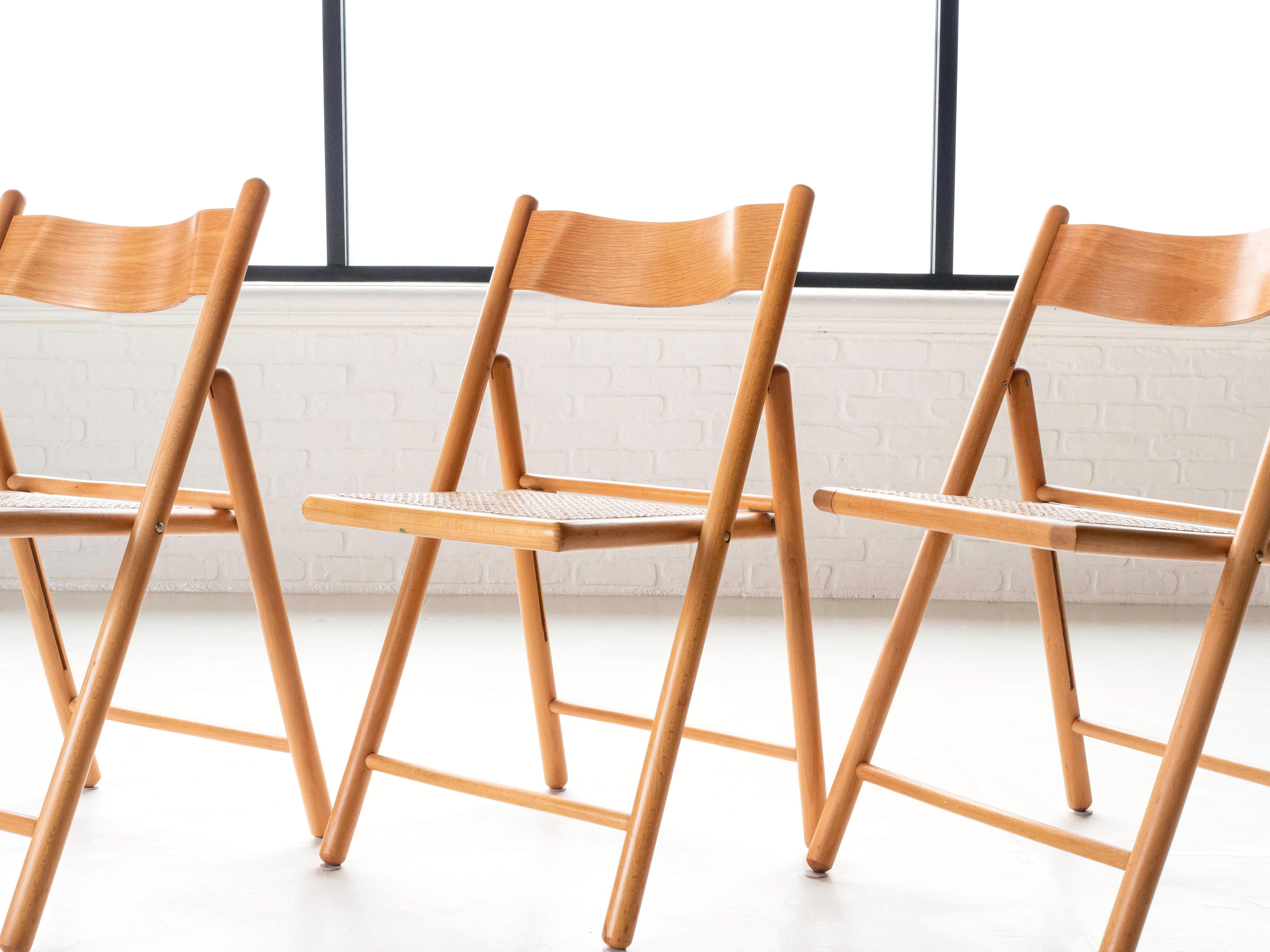 A set of four post modern foldable dining chairs.  Made from solid oak frames and beech backrests.  Cane seats that are in excellent condition.  The chairs have 