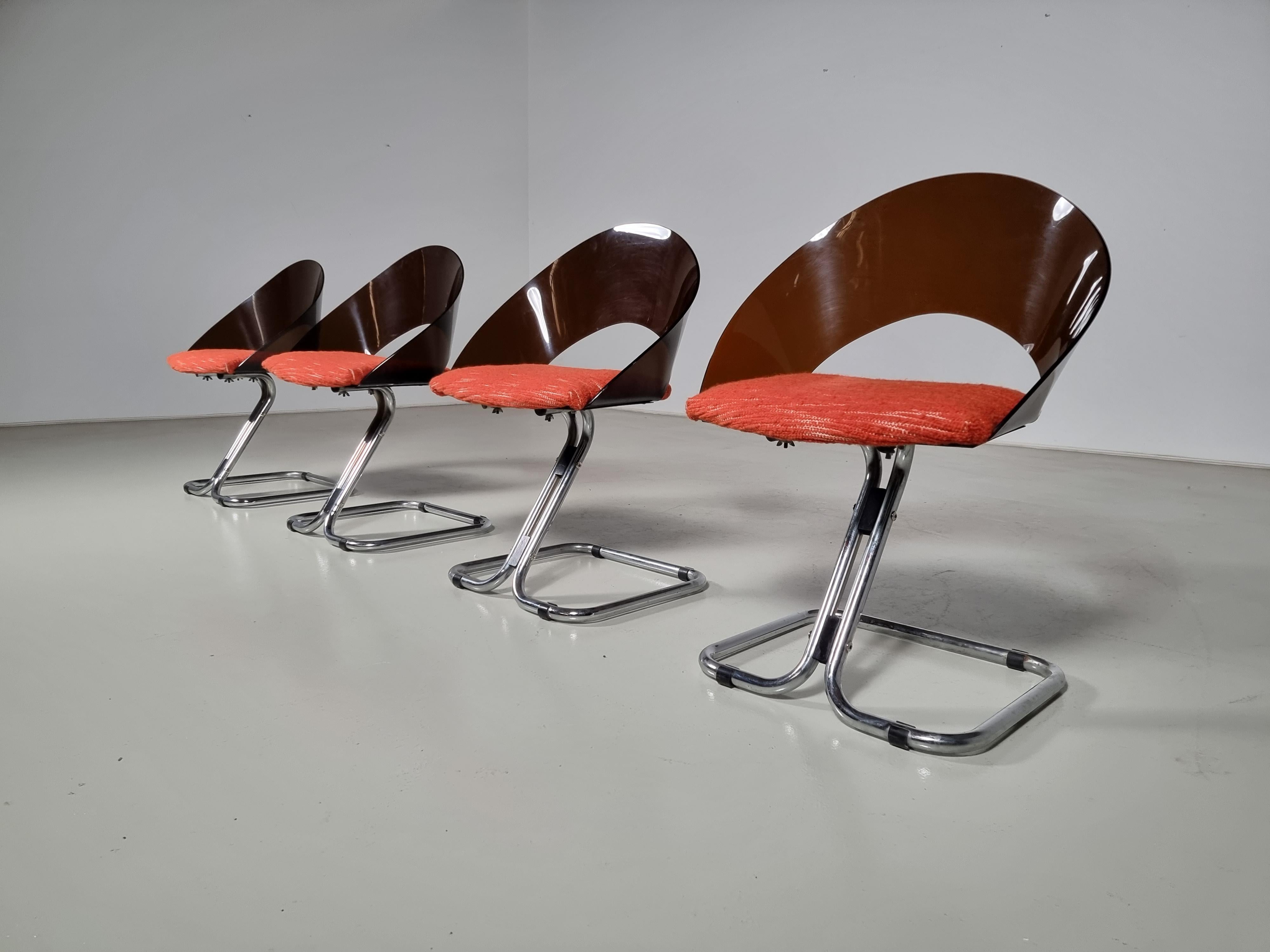Midcentury space-age design dining chairs from the 1970s. Featuring a chromed tubular base with smoked plexiglass backrests, and new upholstered orange fabric cushions. Fabric by La Maison Pierre Frey.

